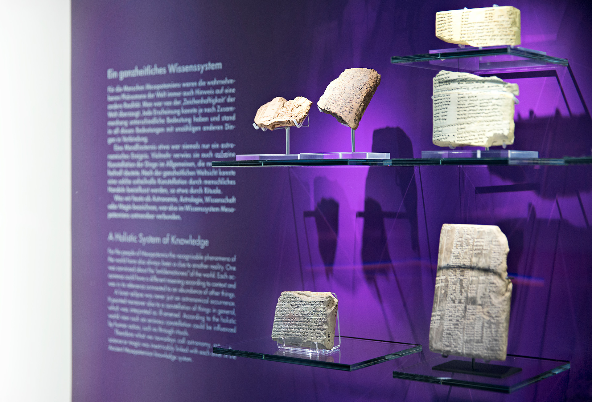 Wandvitrine mit violetter Rückwand. Gezeigt werden alte Steintafeln mit eingravierter Schrift