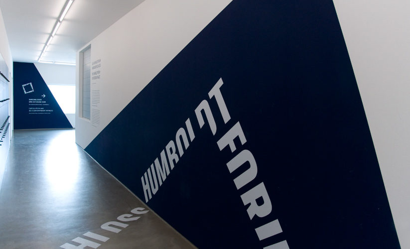 Ausstellungswand mit dunkelblauem Dreieck auf dem "Humboldt Forum" steht