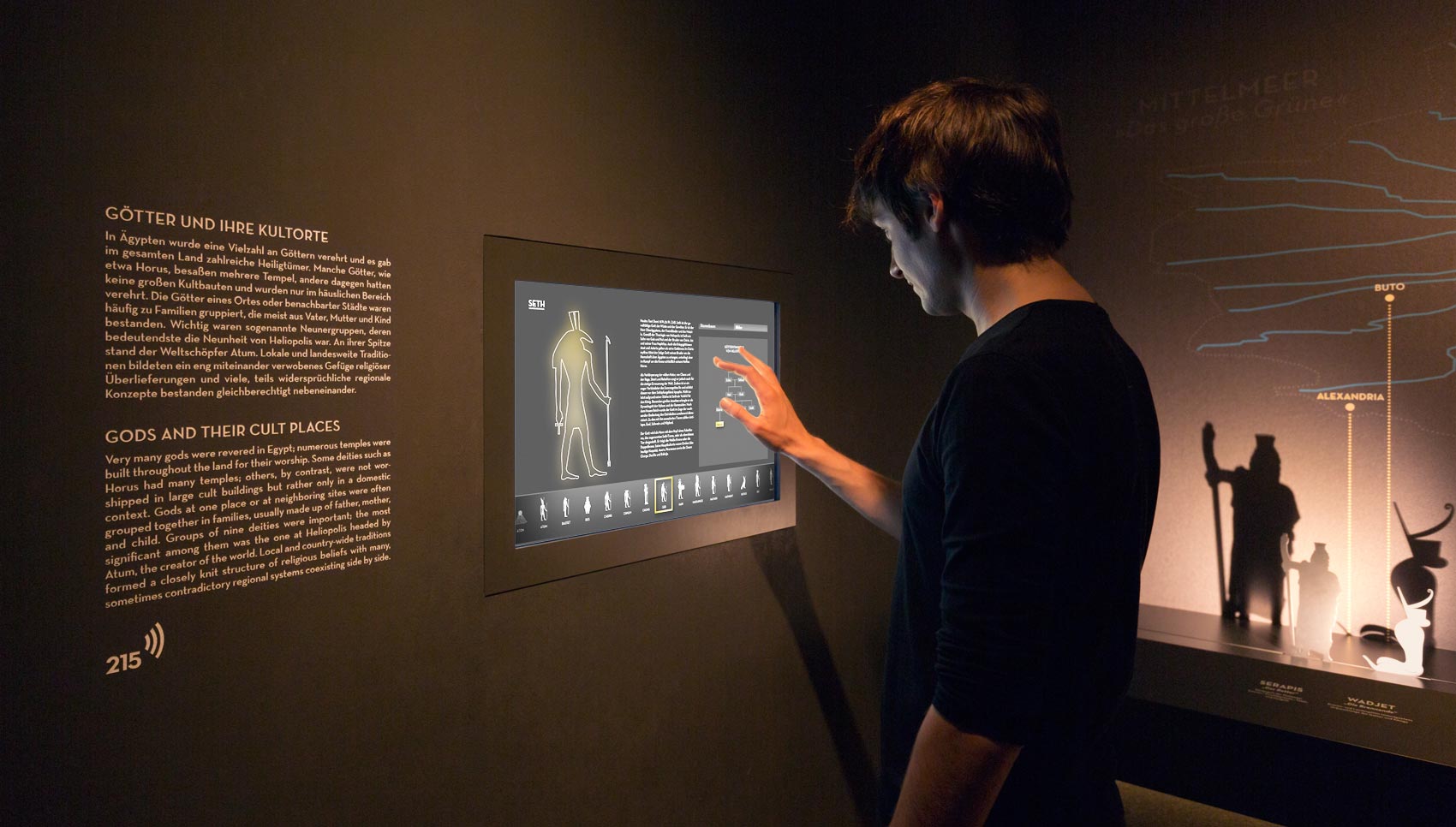 Besucher interagiert mit Medienstation Thema "Götter und ihre Kultorte"