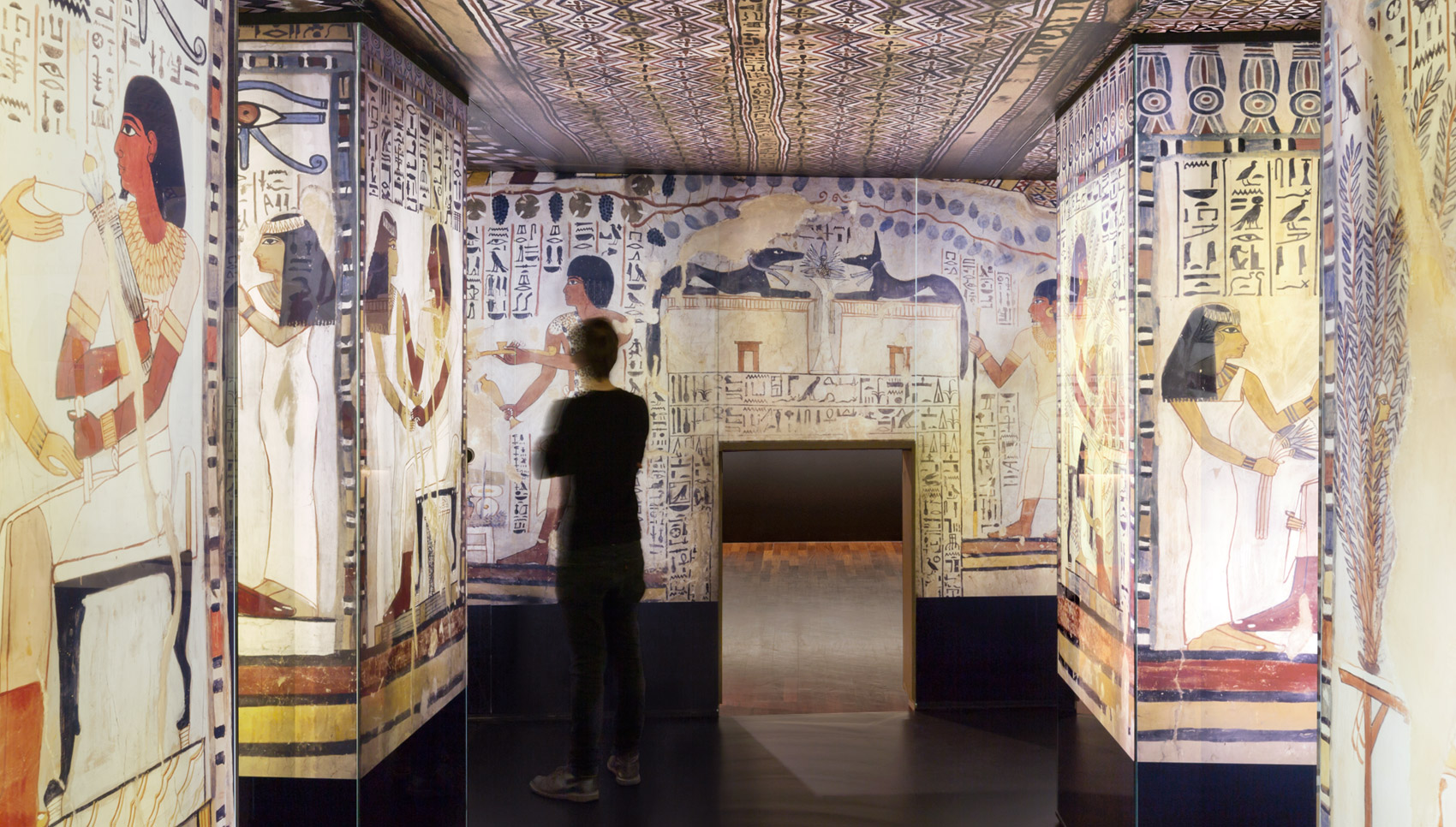 Besucher steht in Raum mit hinterleuchteten Fotowänden ägyptischer Malereien