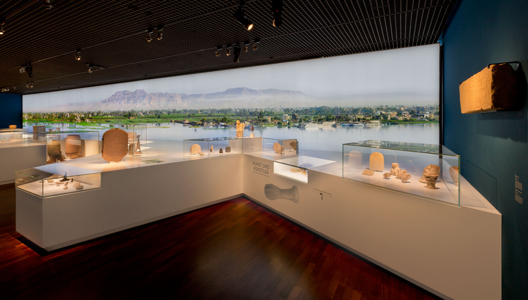 Blick in Ausstellungsraum mit vielen weißen Tischpodesten auf denen verschiedene Aufsatzvitrinen zu sehen sind