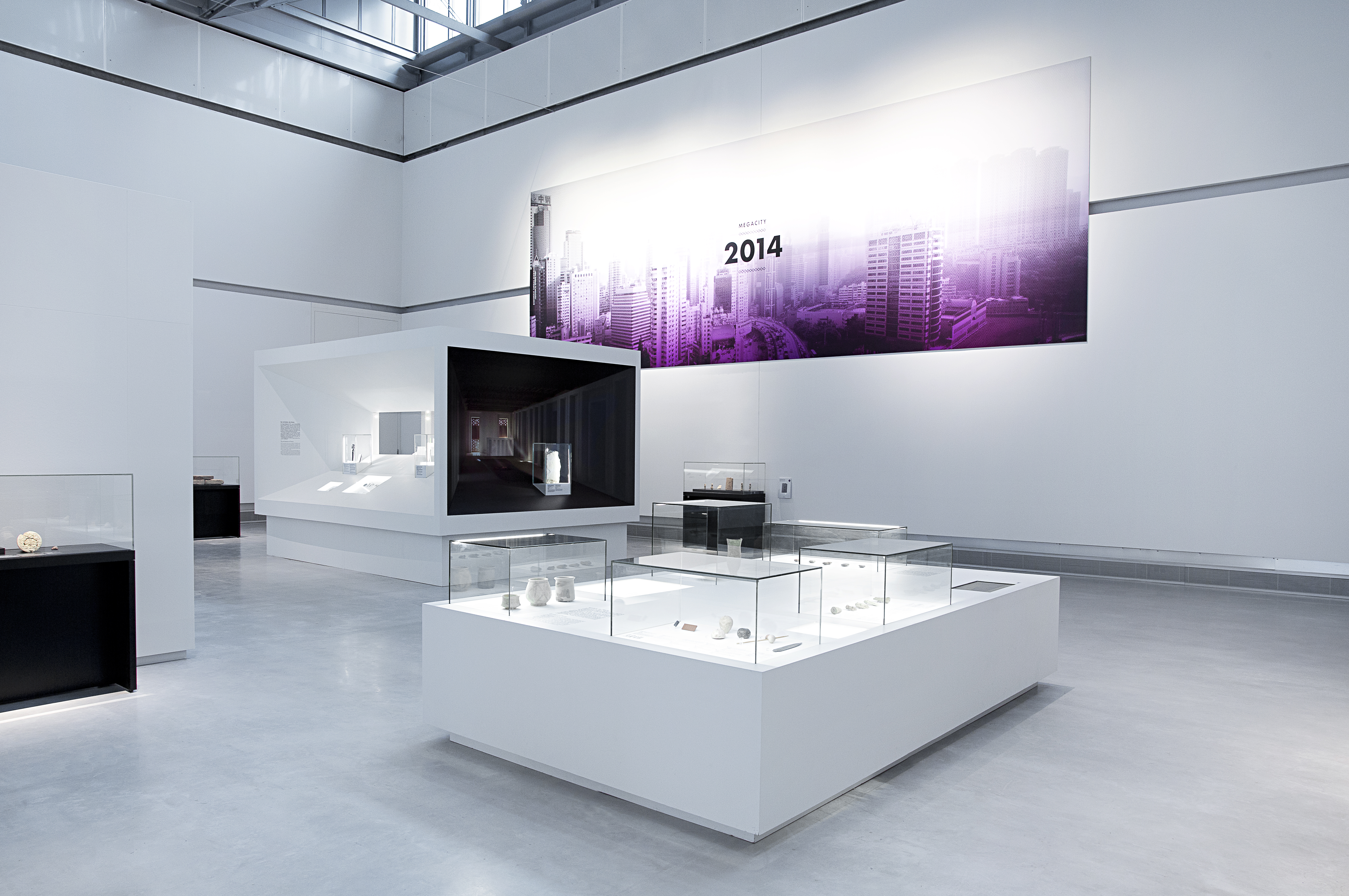 großes weißes Tischpodest mit verschiedenen Aufsatzvitrinen und flächig verbautem Medienmonitor