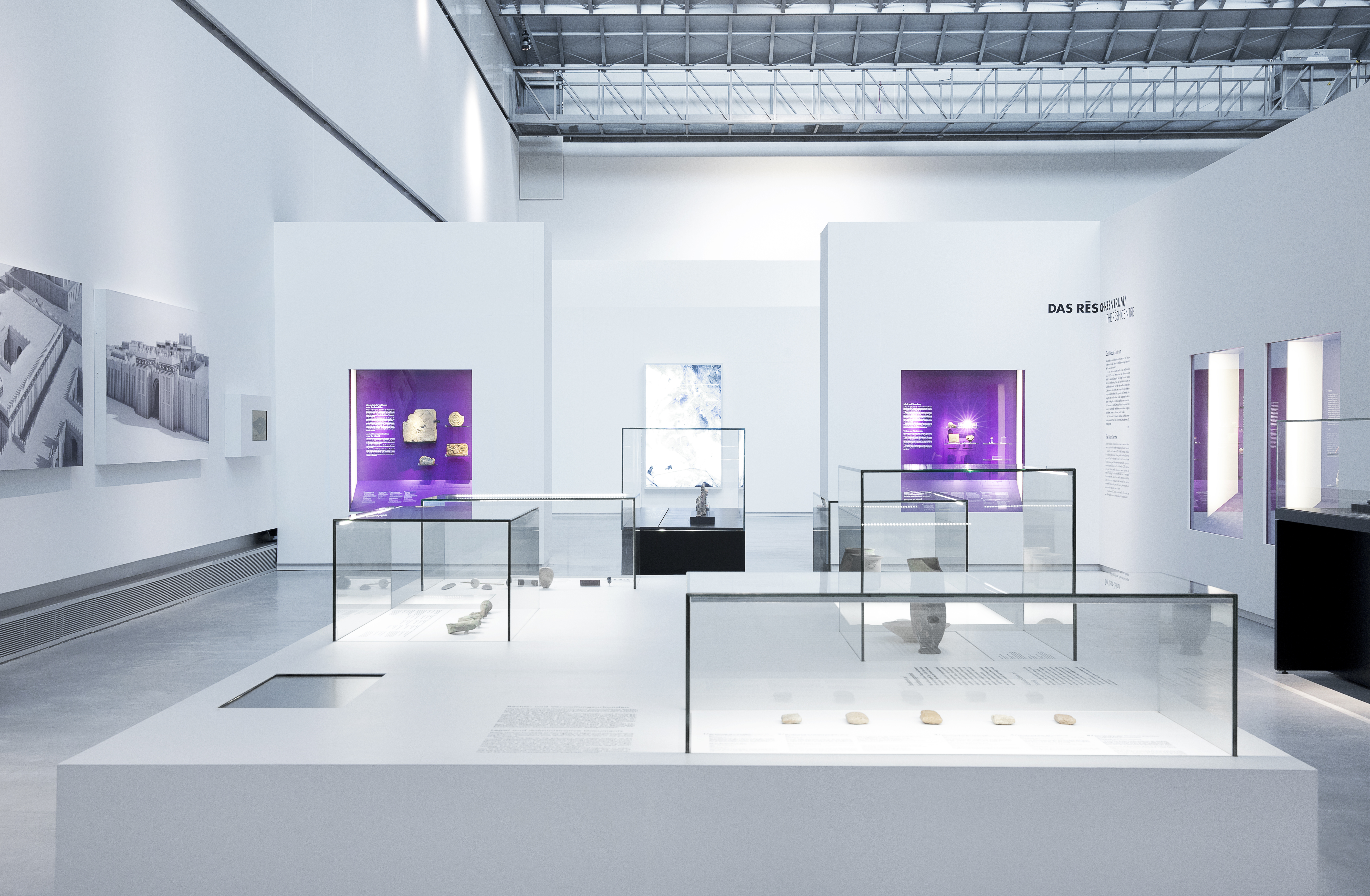 großes weißes Tischpodest mit verschiedenen Aufsatzvitrinen und flächig verbautem Medienmonitor