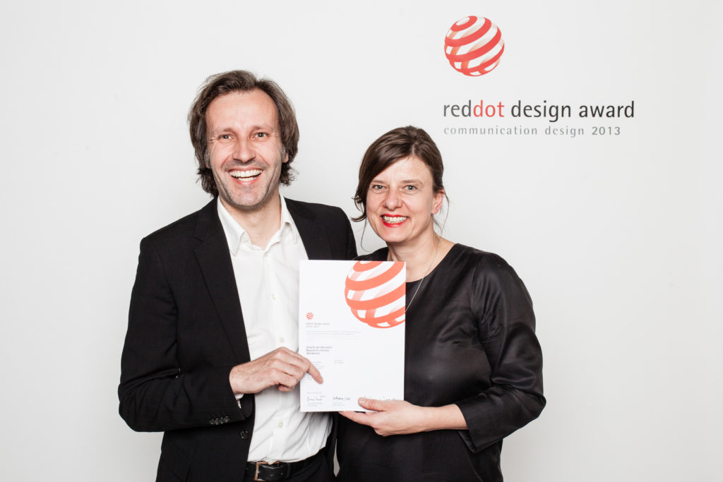 Mann und Frau halten Urkunde von RedDot Design Award in der Hand