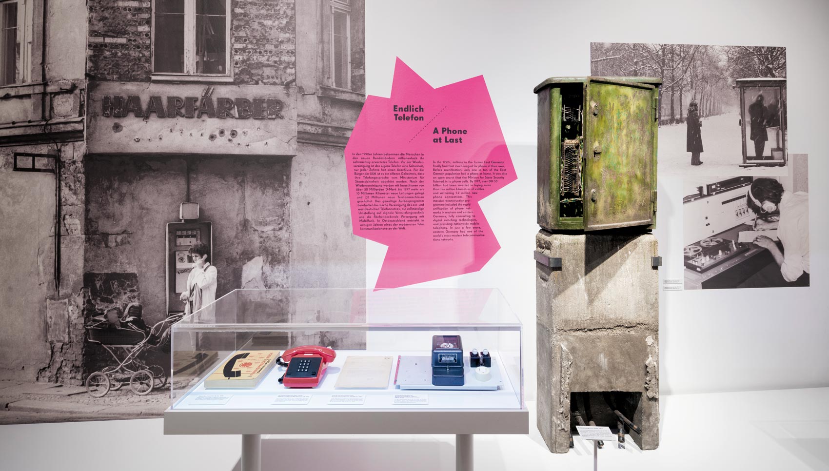 Aufsatzvitrine mit Schnurtelefon vor Wandgrafik "Endlich Telefon"