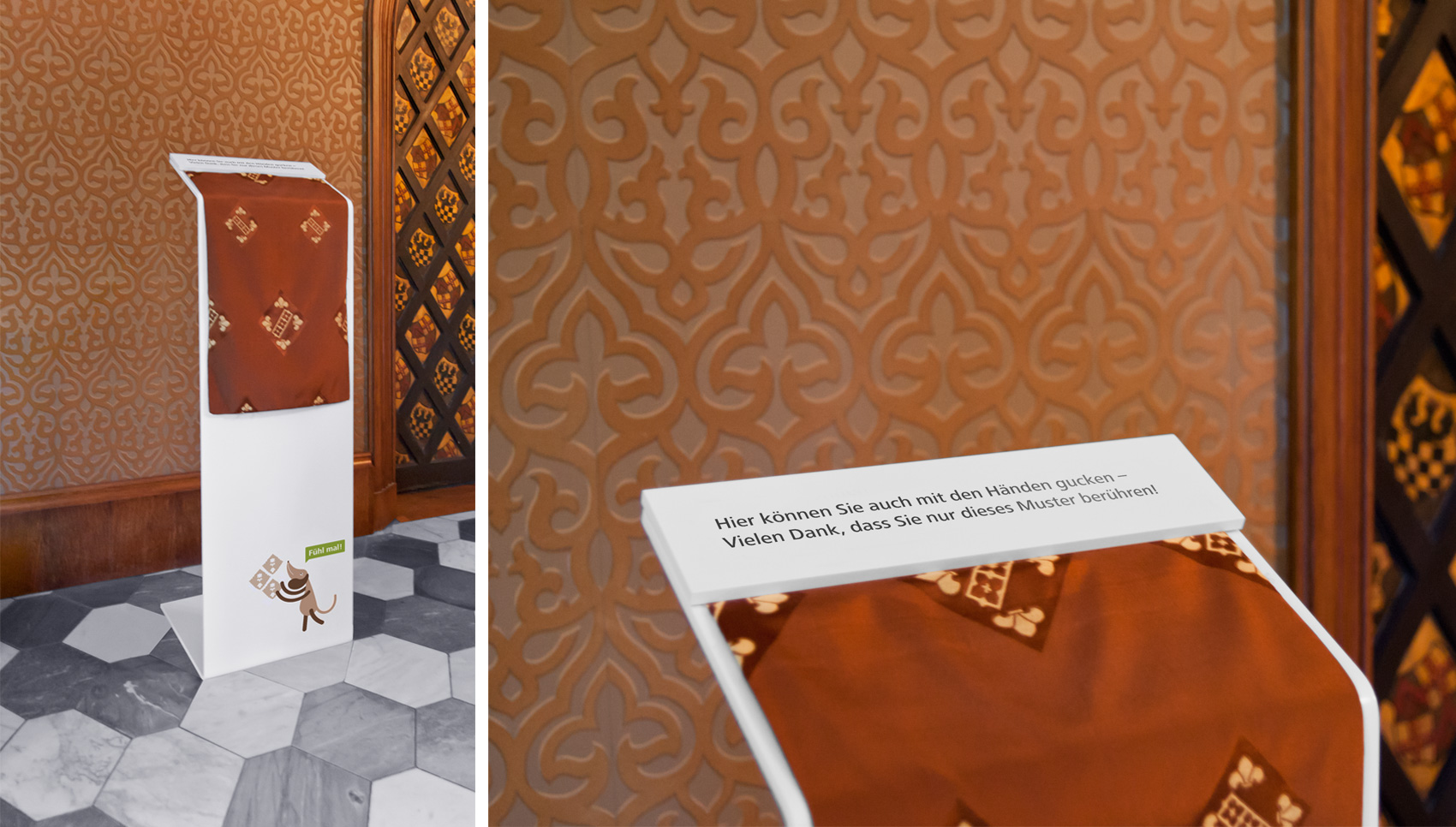 weiße Stehle mit Stoffmuster und Text "Hier können Sie auch mit den Händen gucken – Vielenk Dank, dass Sie nur dieses Muster berühren"