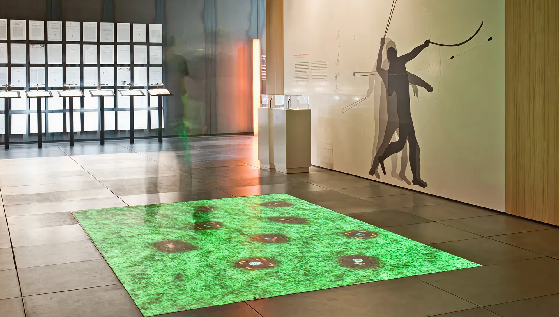 Blick in Raum. Auf dem Boden Projektion einer grünen Wiese mit verschiedenen Fundorten darin.