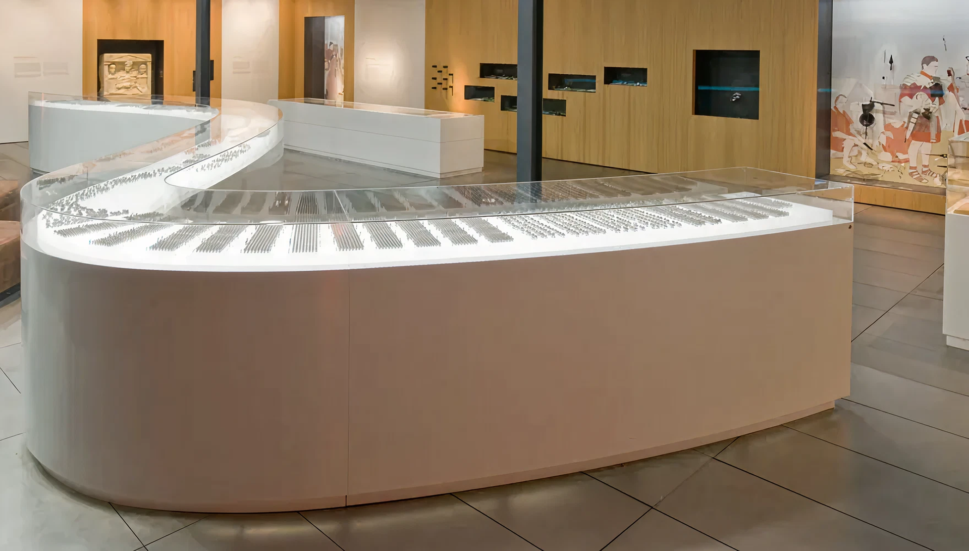 schlangenförmiges Tischpodest mit kompletter Aufsatzvitrine. Darin zu sehen kleine Figuren in verschiedenen militärischen Formationen.