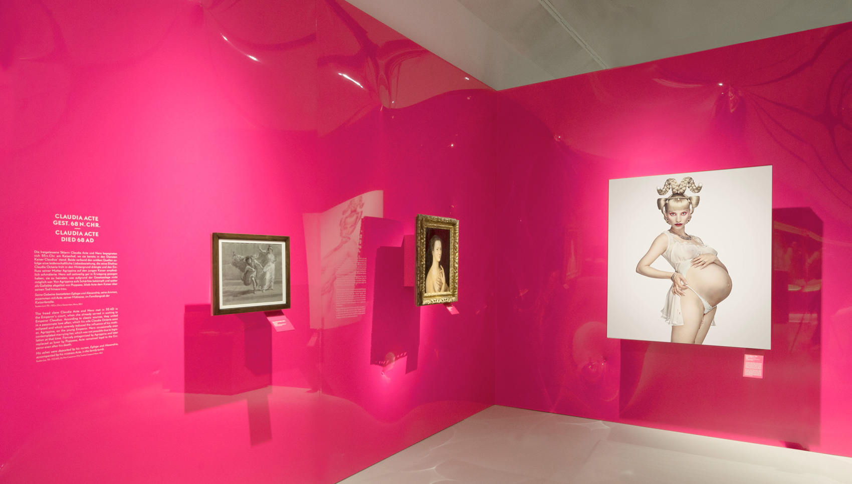 Ausstellungsraum mit pinken Wänden mit Fokus auf Foto einer schwangeren Frau