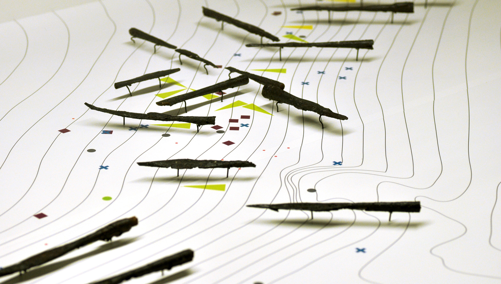 Nahaufnahme einer topografischen Karten mit darüber befindlichen Exponaten "Pfeilspitzen"