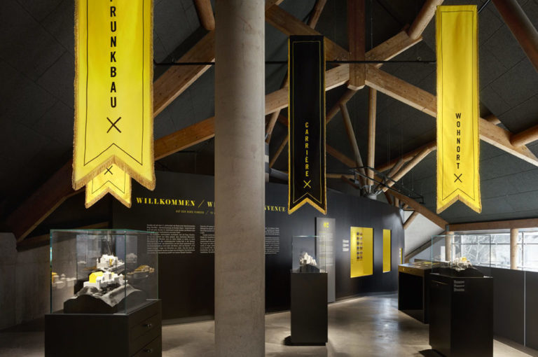 Ausstellungsraum mit schwarzen Ausstellungsmöbeln mit gelb-leuchtenden Akzenten