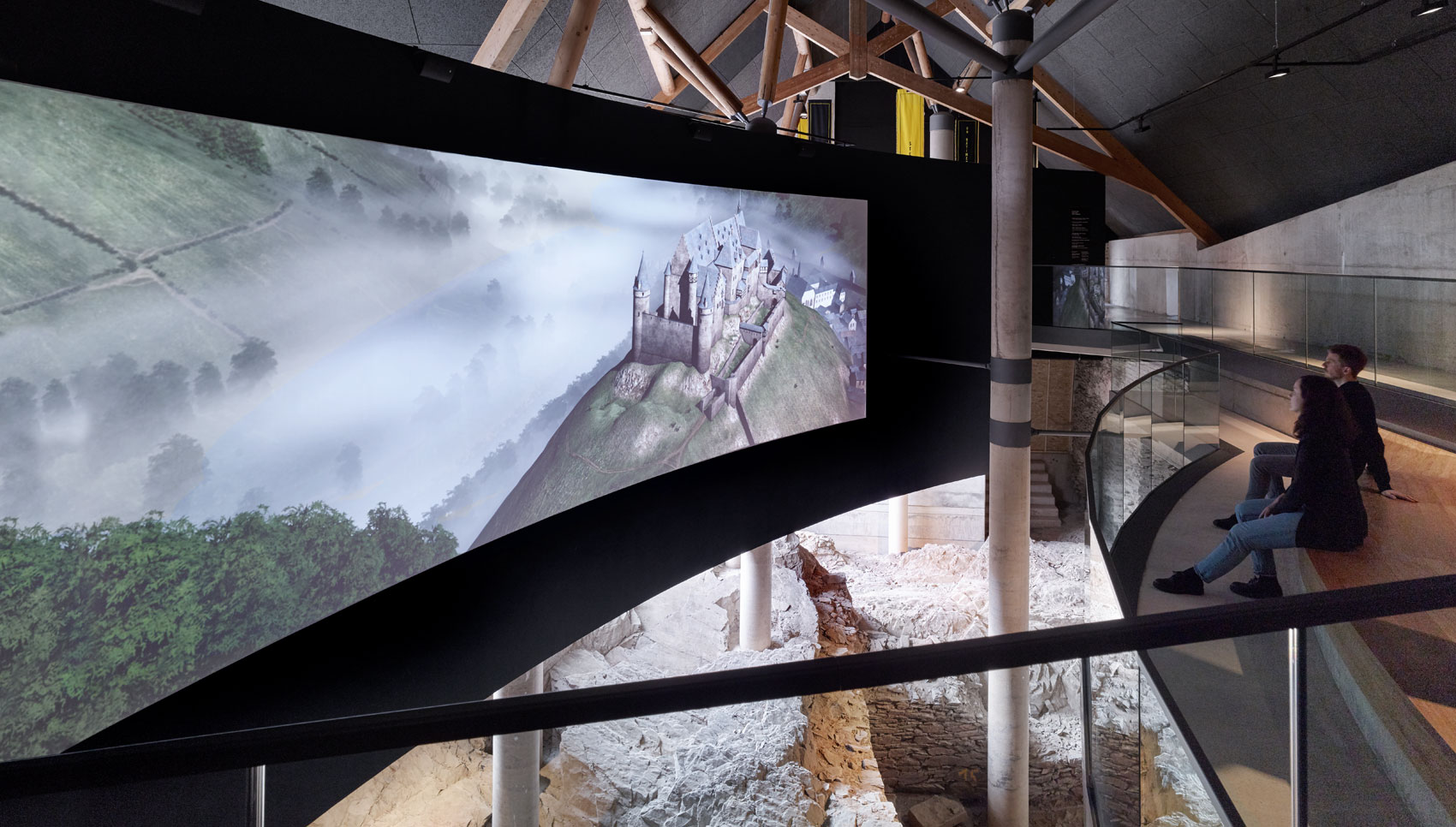 Zwei Menschen gucken sich sitzend einen Film auf einer großen Leinwand an