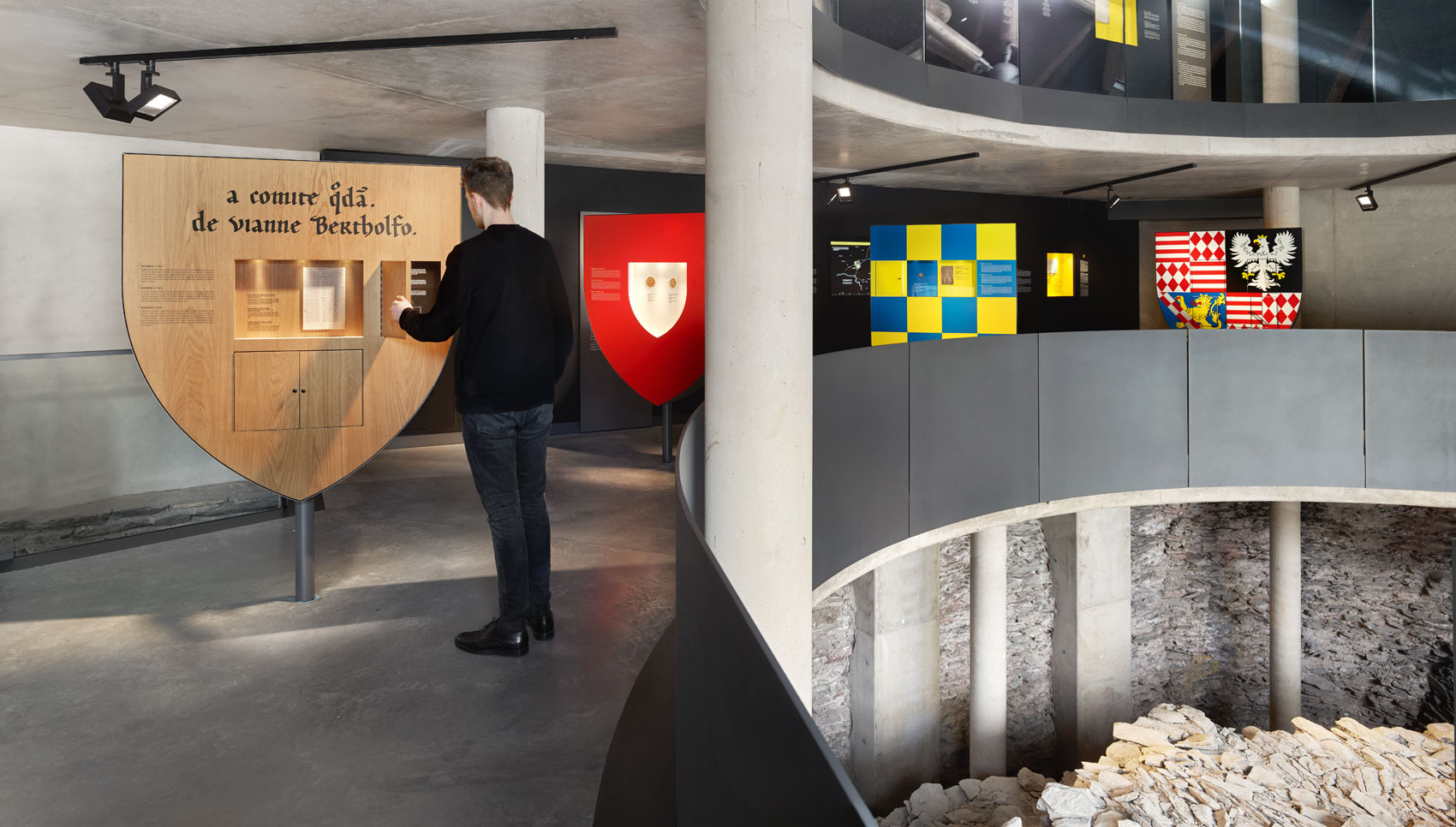 Mann steht im Ausstellungsraum vor einem interakiven Ausstellungsmöbel