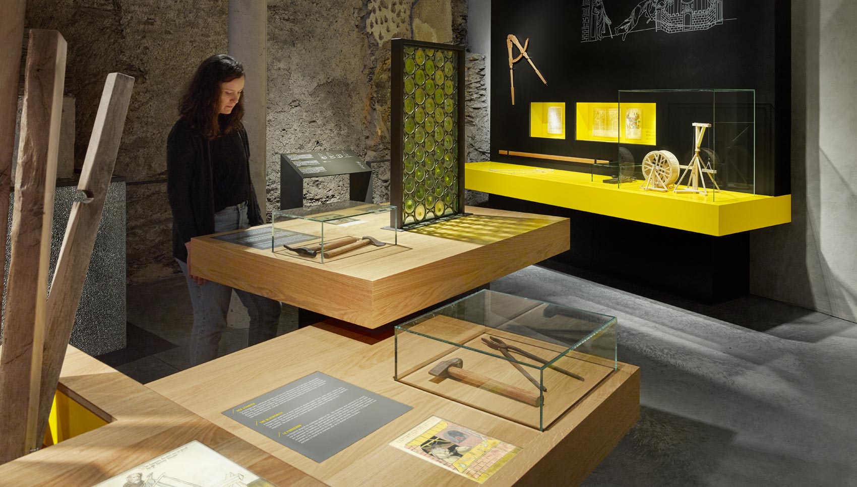 Frau steht im Ausstellungsraum vor Ausstellungsmöbeln und verschiedenen Exponaten