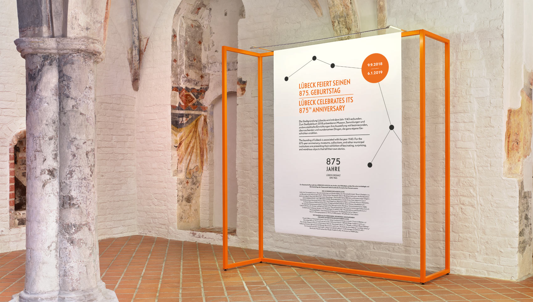 Ausstellungsraum mit Ausstellungsmöbel, bei dem Stoffbanner auf organgefarbigen Stangen hängen