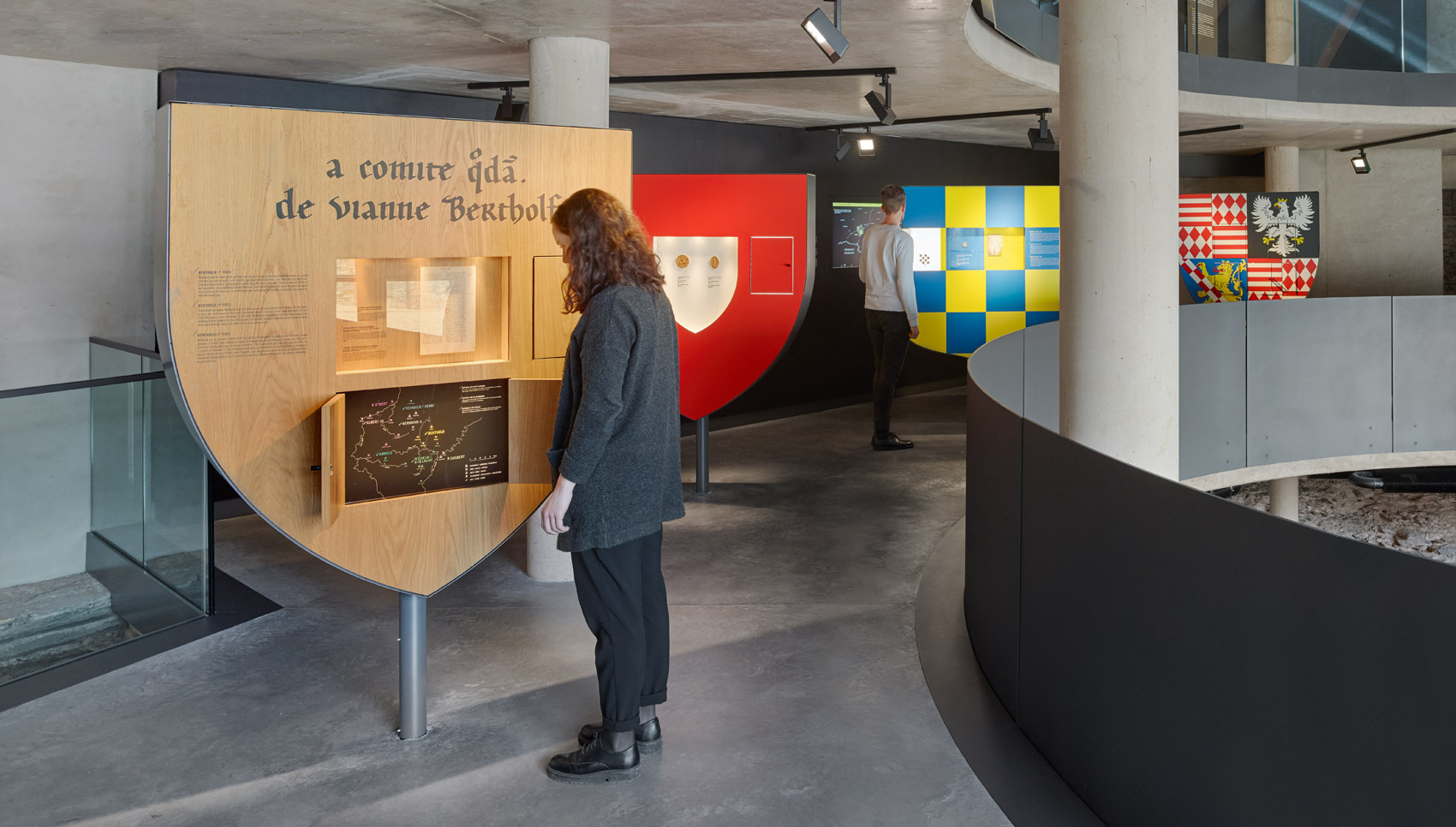 Frau steht im Ausstellungsraum vor einem interakiven Ausstellungsmöbel