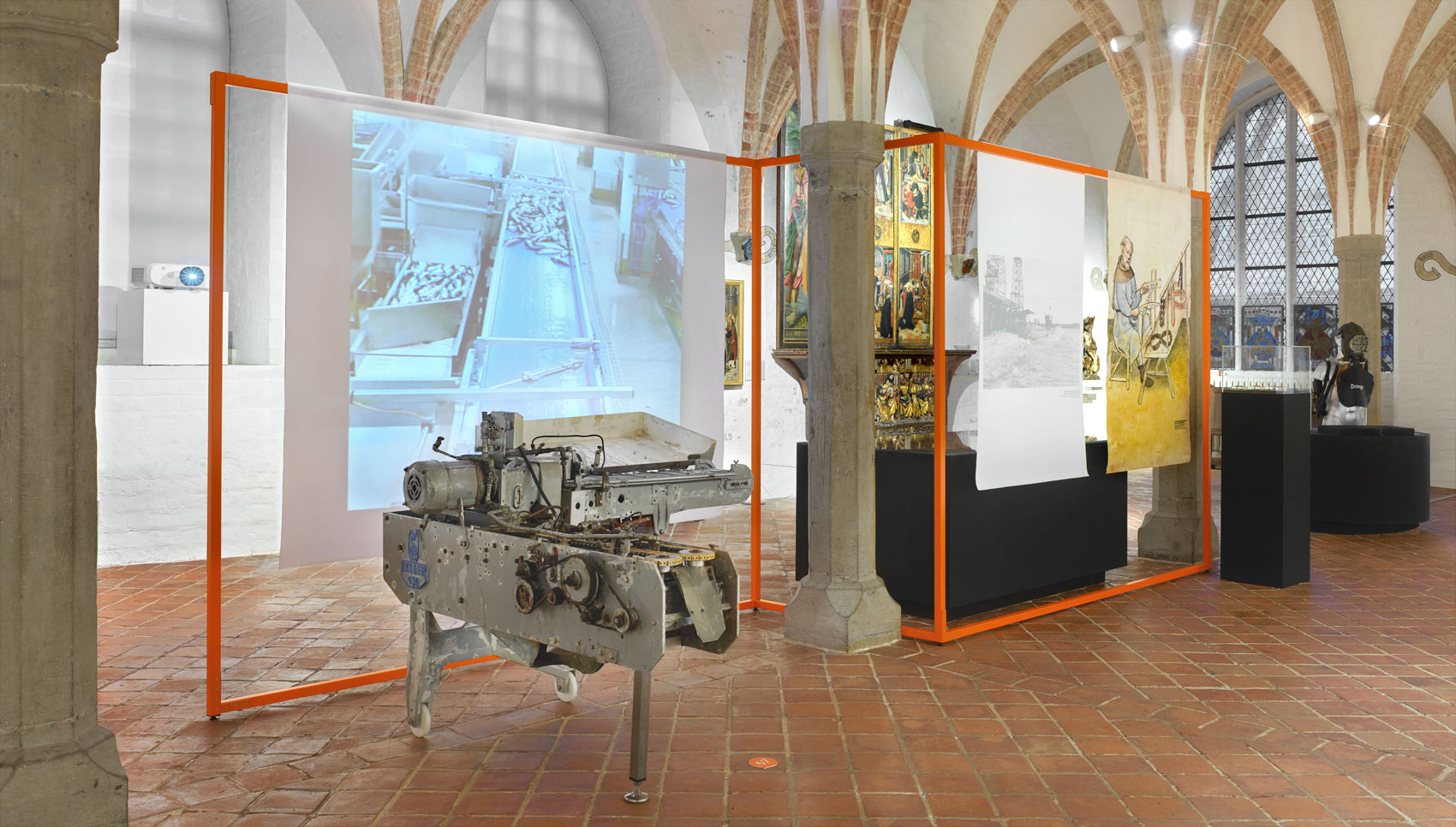 Ausstellungsraum mit Ausstellungsmöbel, bei dem Stoffbanner auf organgefarbigen Stangen hängen