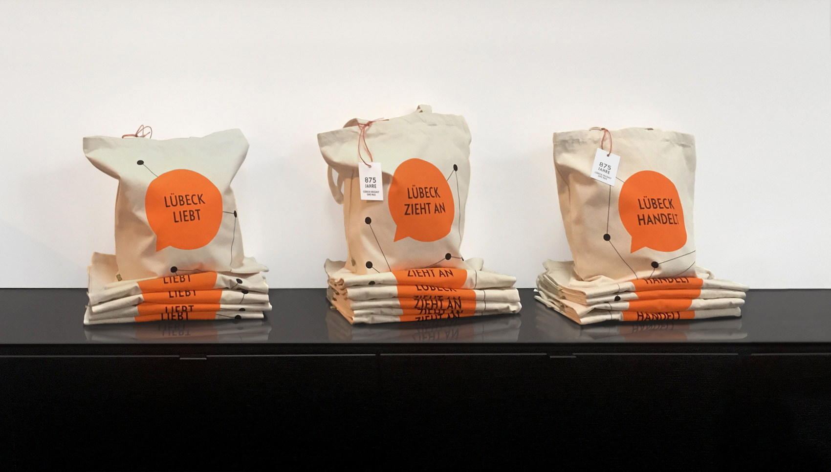 Jutebeutel mit Beschriftung: "Lübeck liebt", "Lübeck zieht an", "Lübeck handelt"