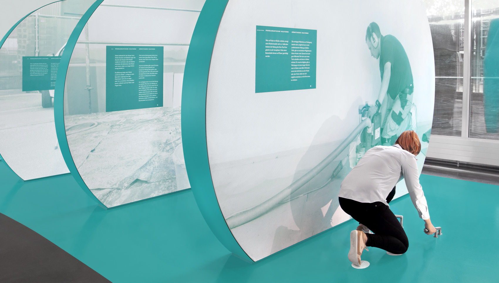 Frau kniet im Ausstellungsraum und bedient ein interaktives Ausstellungsstück