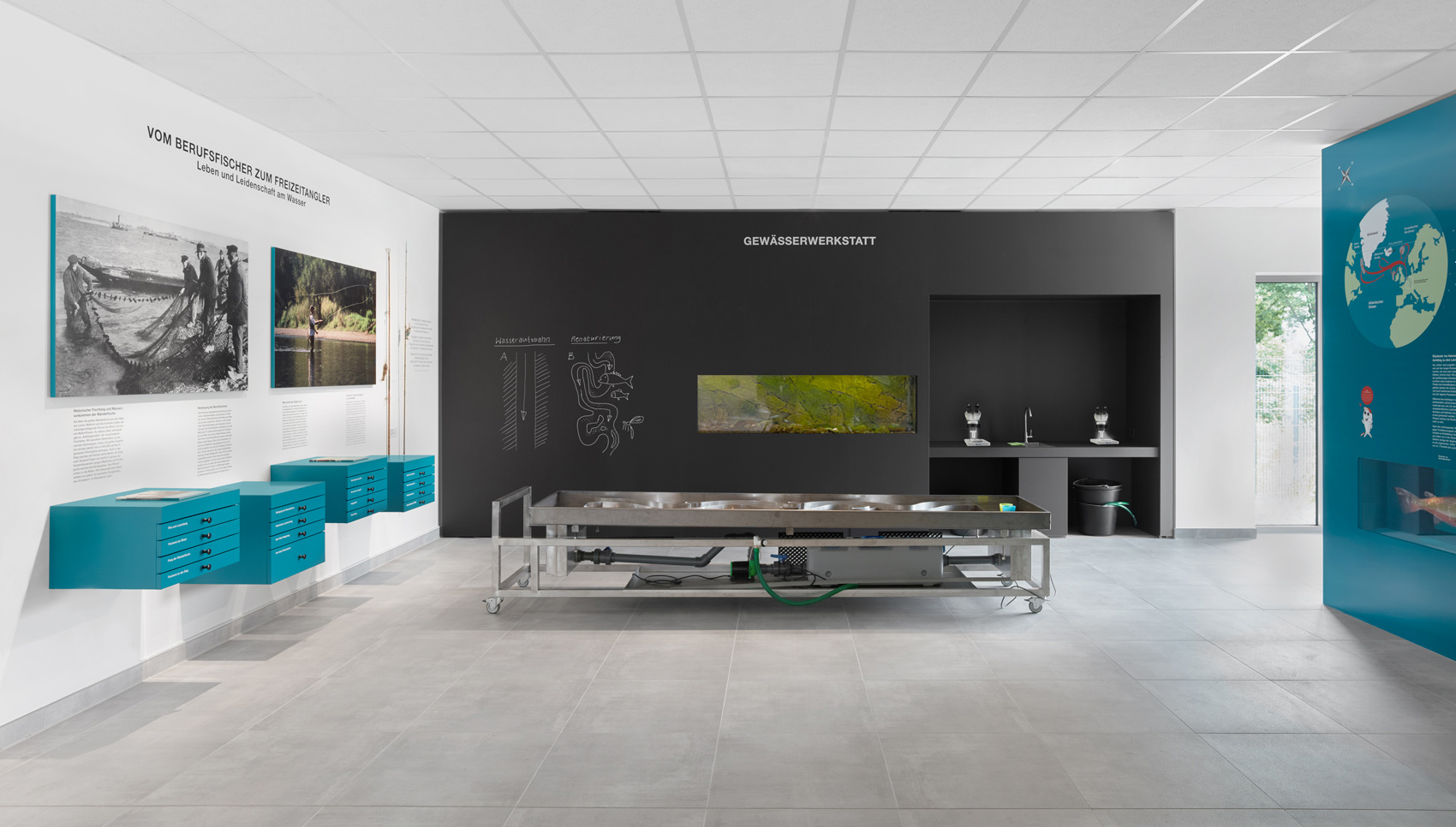 Ausstellungsraum mit Blick auf eine große schwarze Wand mit der Überschrift "Gewässerwerkstatt"