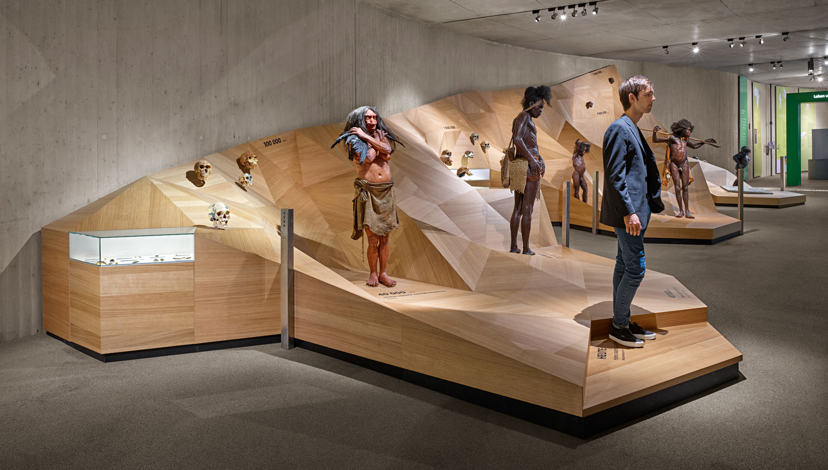 Ausstellungspodest aus Holz mit verschiedenen Exponaten, wie zum Beispiel Neanderthaler Figuren