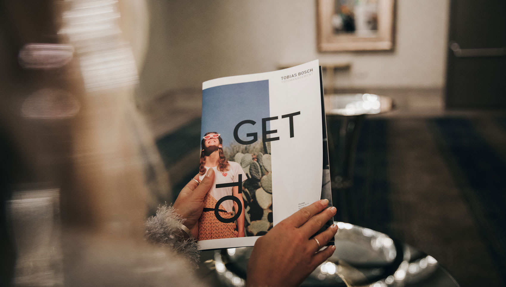 Fotografie der Broschüre "GET TO KNOW", die von einer Person gehalten wird