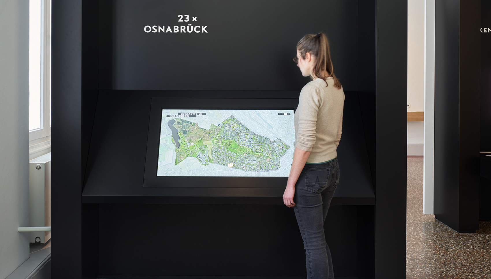 Frau steht vor interaktiven Medienstation