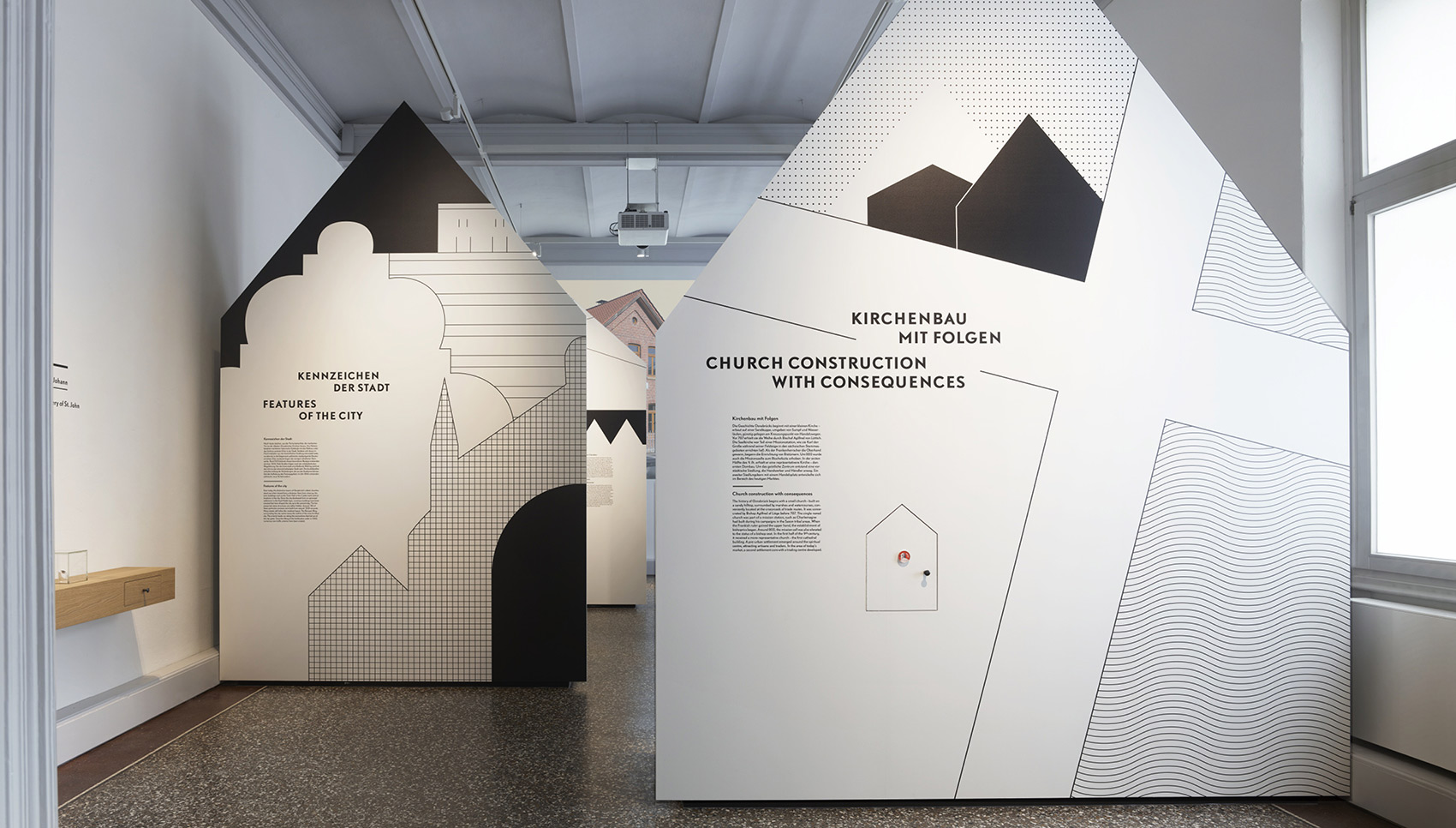 Ausstellungsraum mit größen Trennwänden, die eine Hausform haben