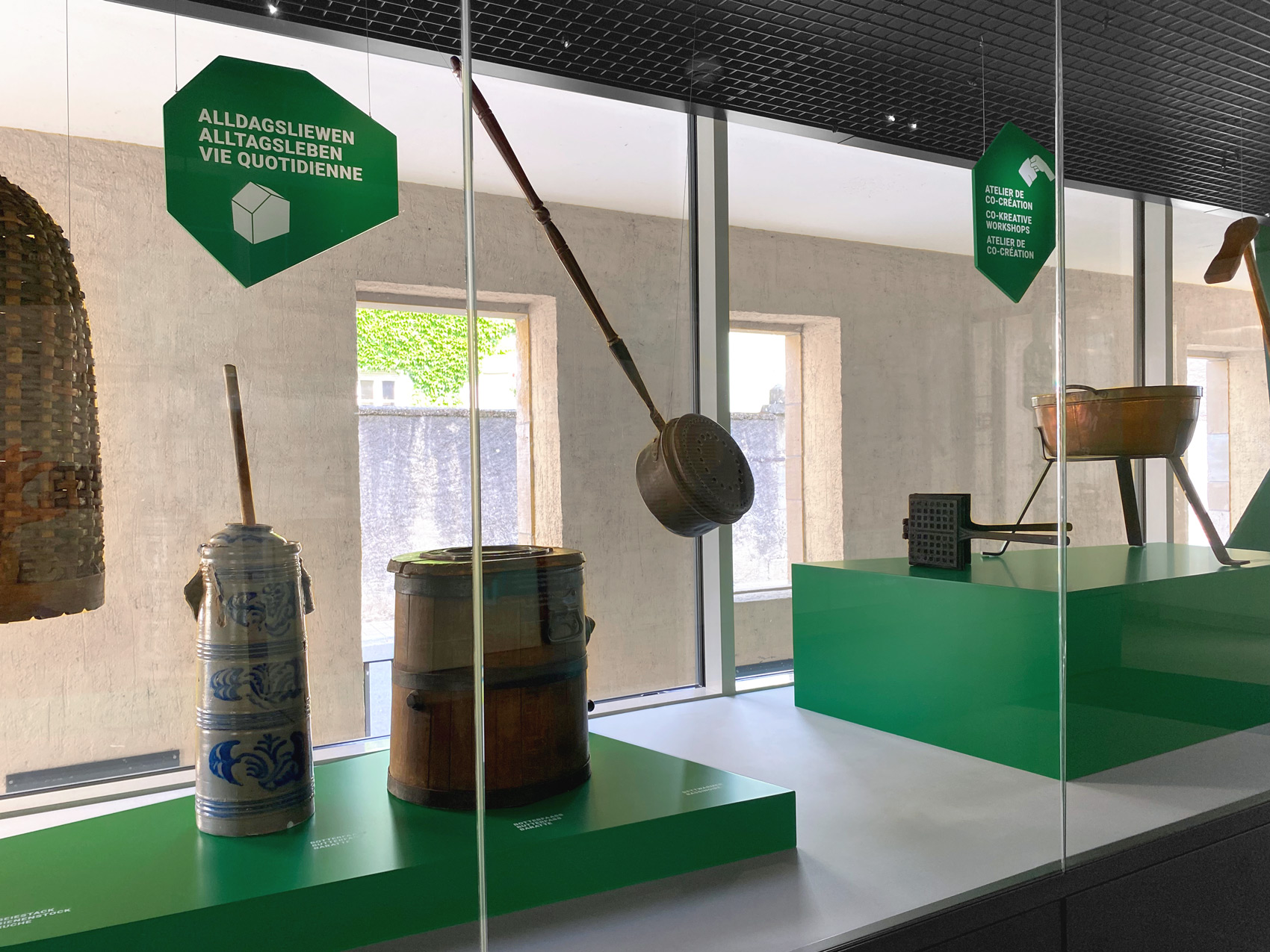 Verschiedene Exponate auf grünen Podesten mit grünen Hängeschildern