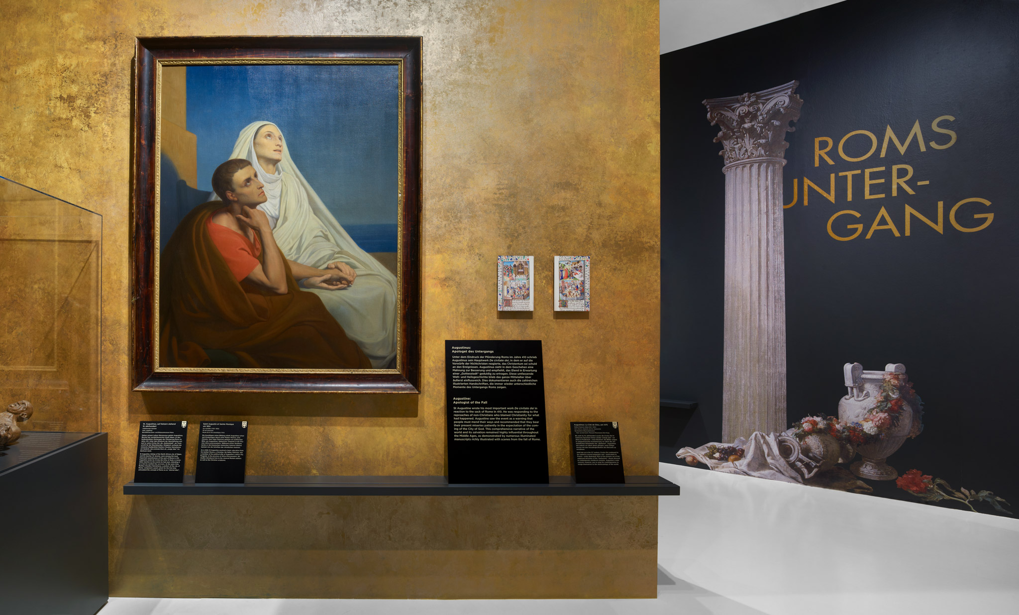 Ausstellungsraum mit goldenen Wänden, Gemälden, Texttafeln und Grafiken