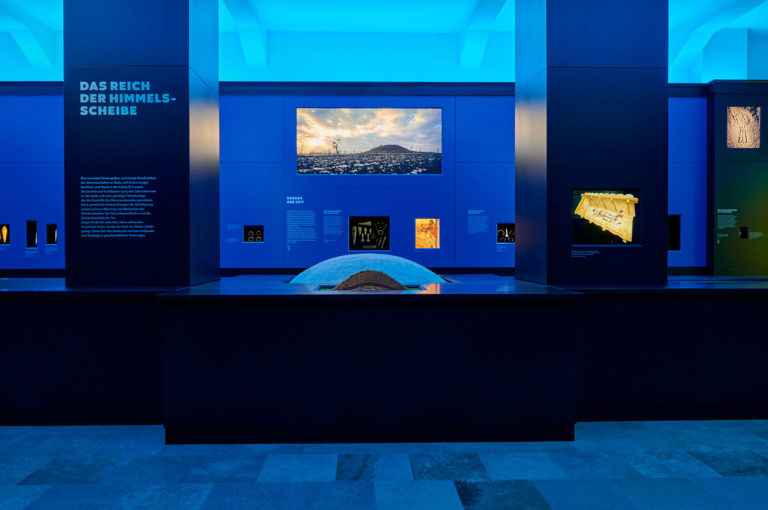 Ausstellungsraum mit Ausstellungsmöbeln und Exponaten in blauem Licht