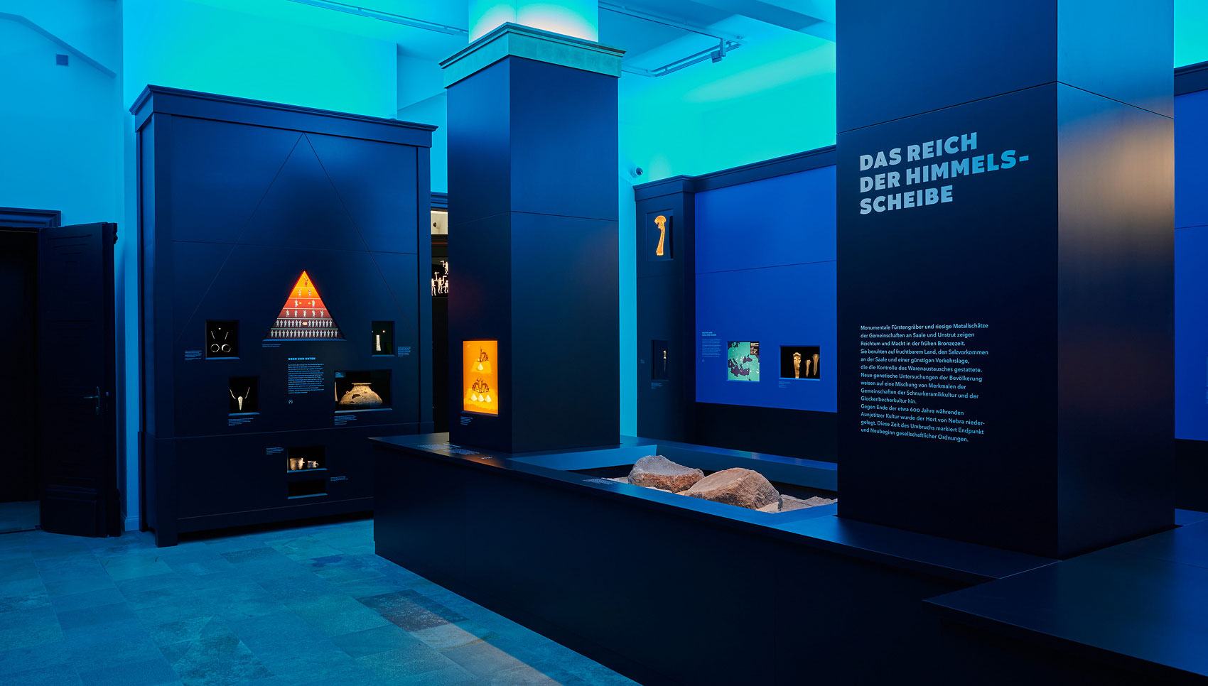 Ausstellungsraum mit Ausstellungsmöbeln und Exponaten in blauem Licht