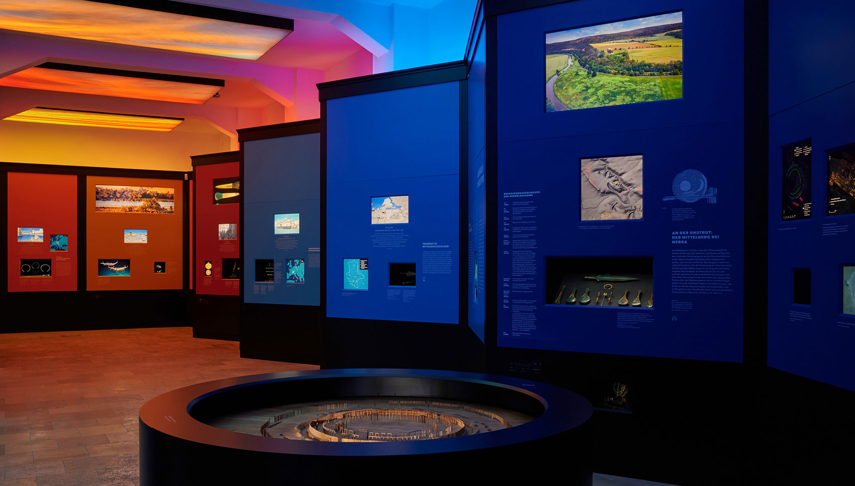 Ausstellungsraum mit Ausstellungsmöbeln und Exponaten mit einem Lichtverlauf von Blau nach Rot