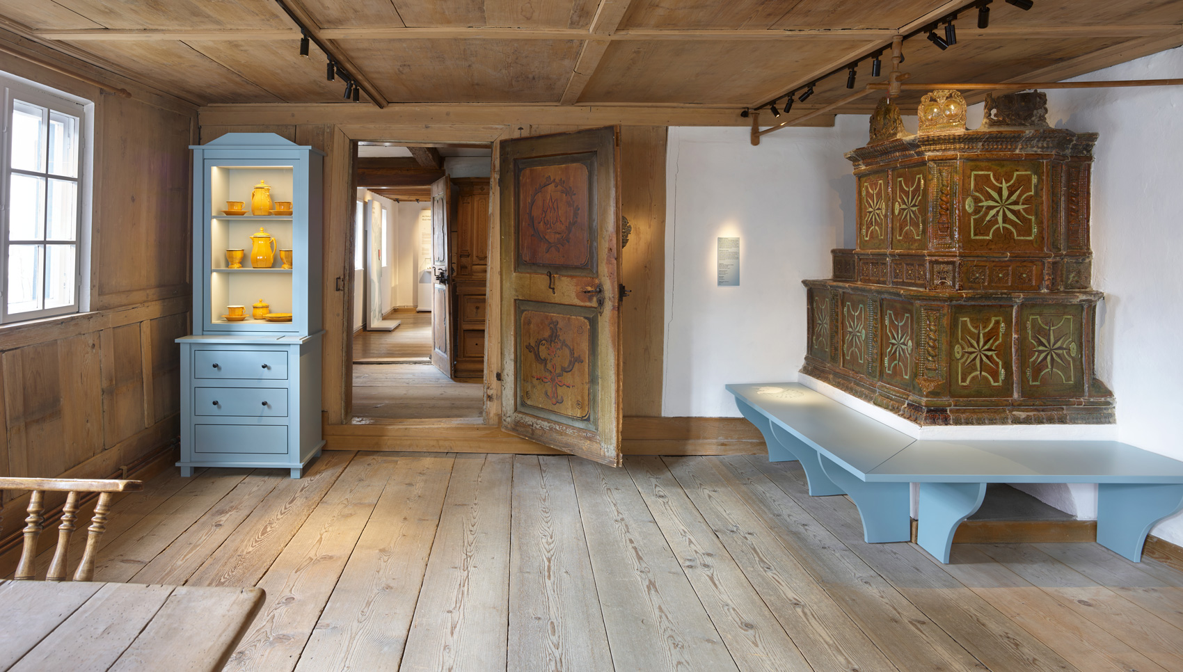 Ausstellungsraum mit Ausstellungsmöbeln und verschiedenen Expnaten – einem Wohnraum eines historischen Bauernhauses nachempfunden.