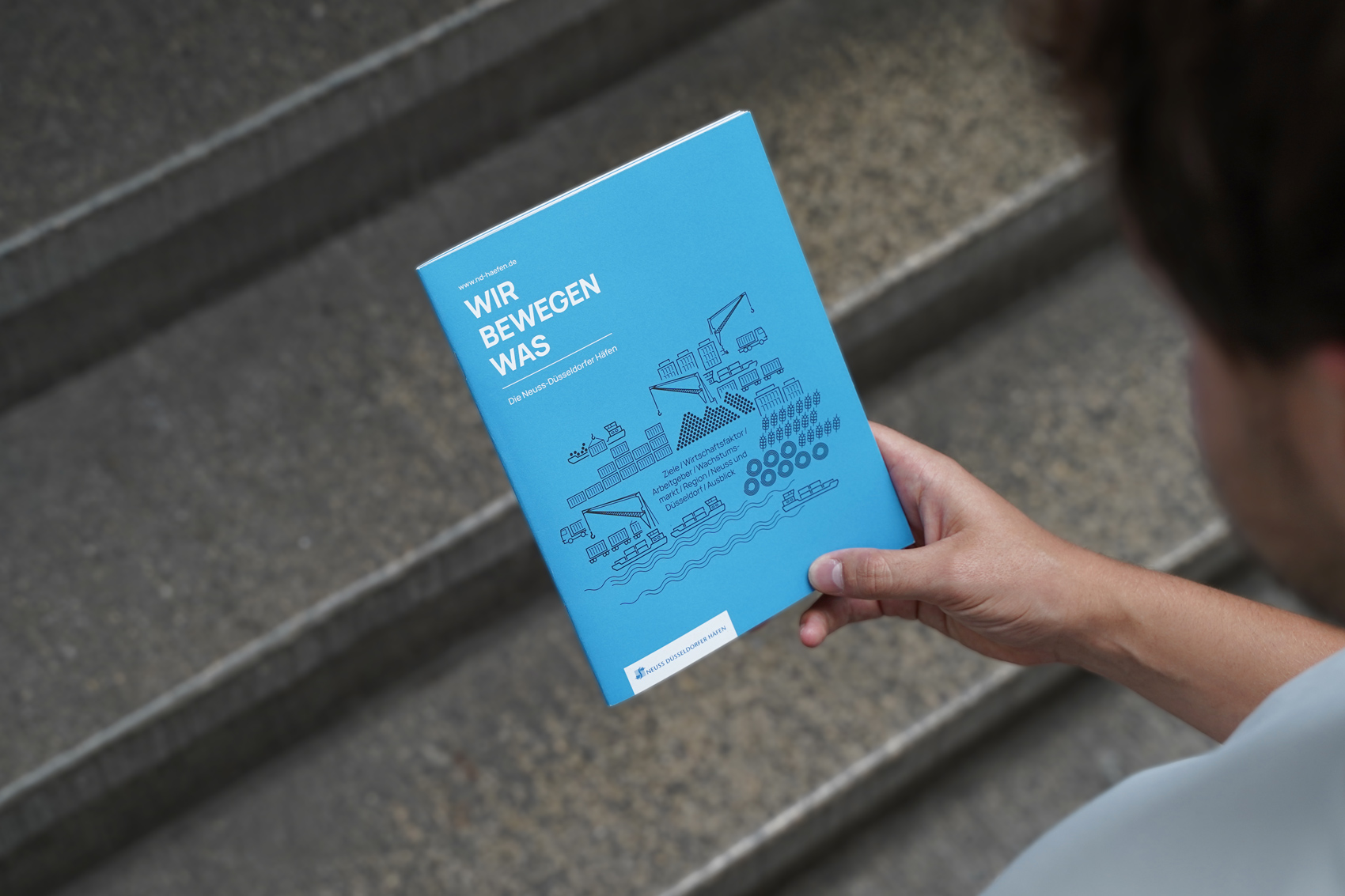 Person hält Broschüre in der Hand. Die Broschüre ist im Fokus.