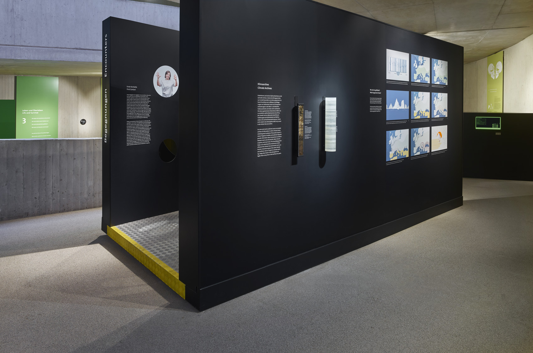 Schwarzes Ausstellungsmöbel mit Grafiken und Exponaten