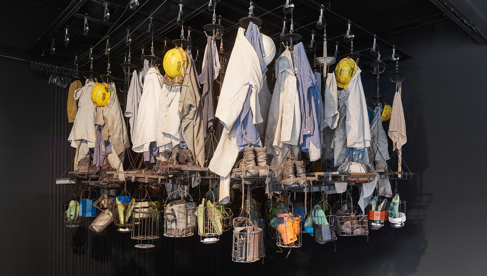 Rauminstallation mit Arbeitskleidung, die von der Decke hängen