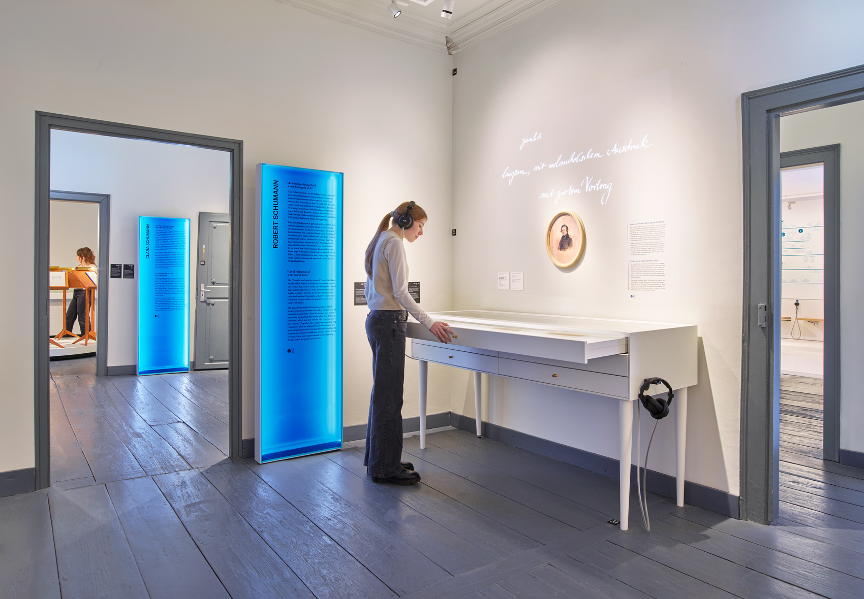 Person im Ausstellungsraum mit interaktivem Ausstellungsmöbeln und verschiedenen Exponaten