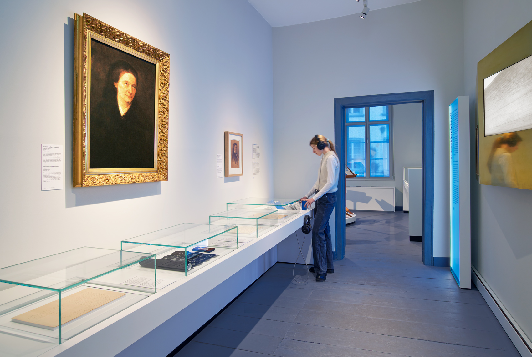 Person im Ausstellungsraum mit interaktivem Ausstellungsmöbeln und verschiedenen Exponaten