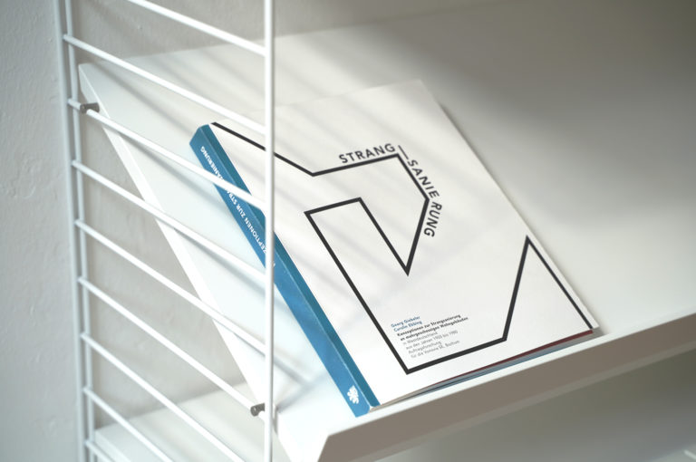 Ansicht des Buches „Strangsanierung“, das in einem Regal liegt