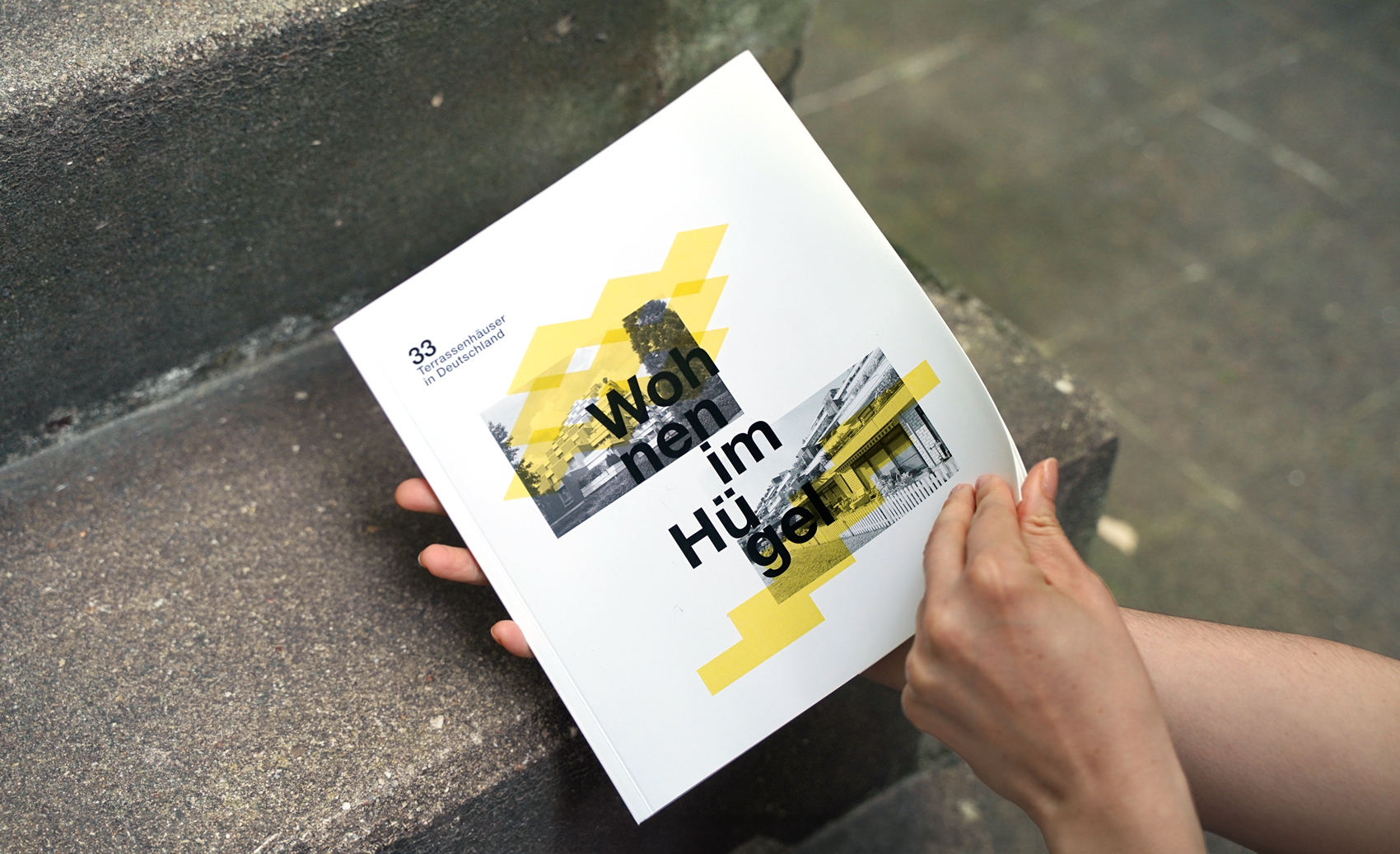 Hände halten das Buch "Terrassenhäuser in Deutschland – Wohnen im Hügel"