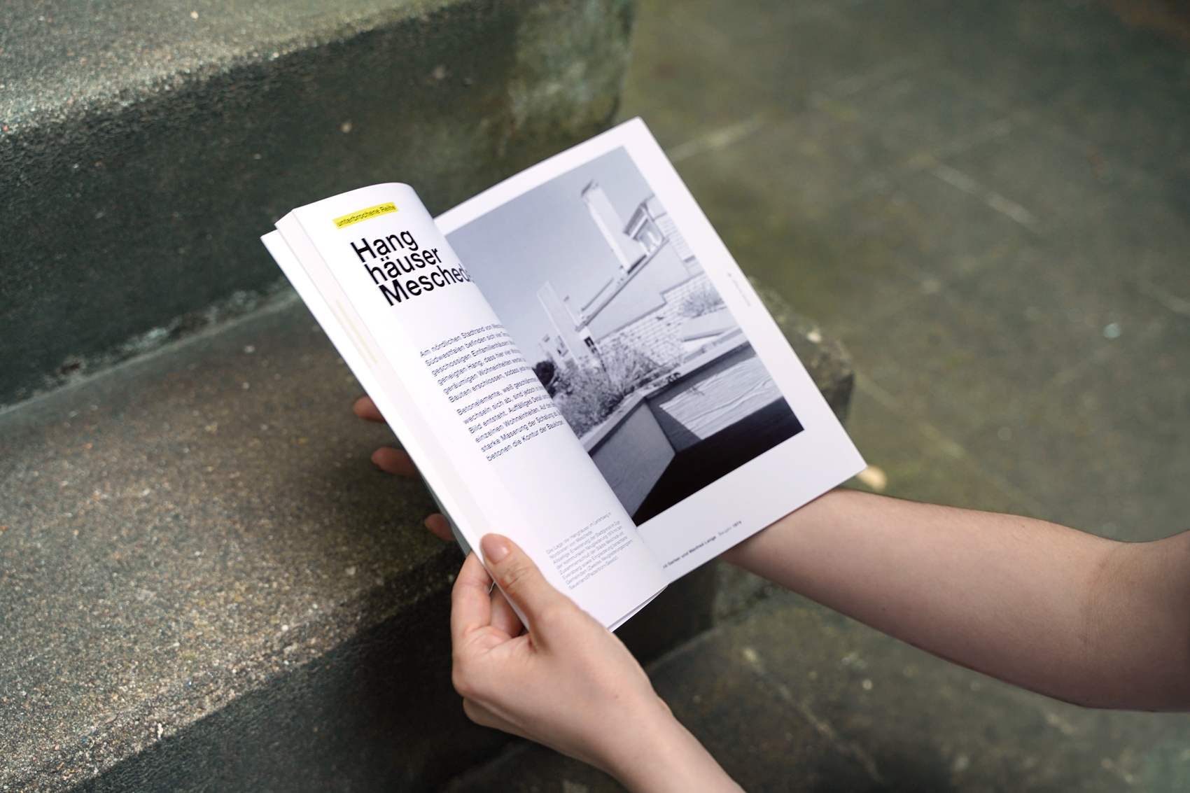 Hände halten das Buch "Terrassenhäuser in Deutschland – Wohnen im Hügel" und schlagen es dabei auf
