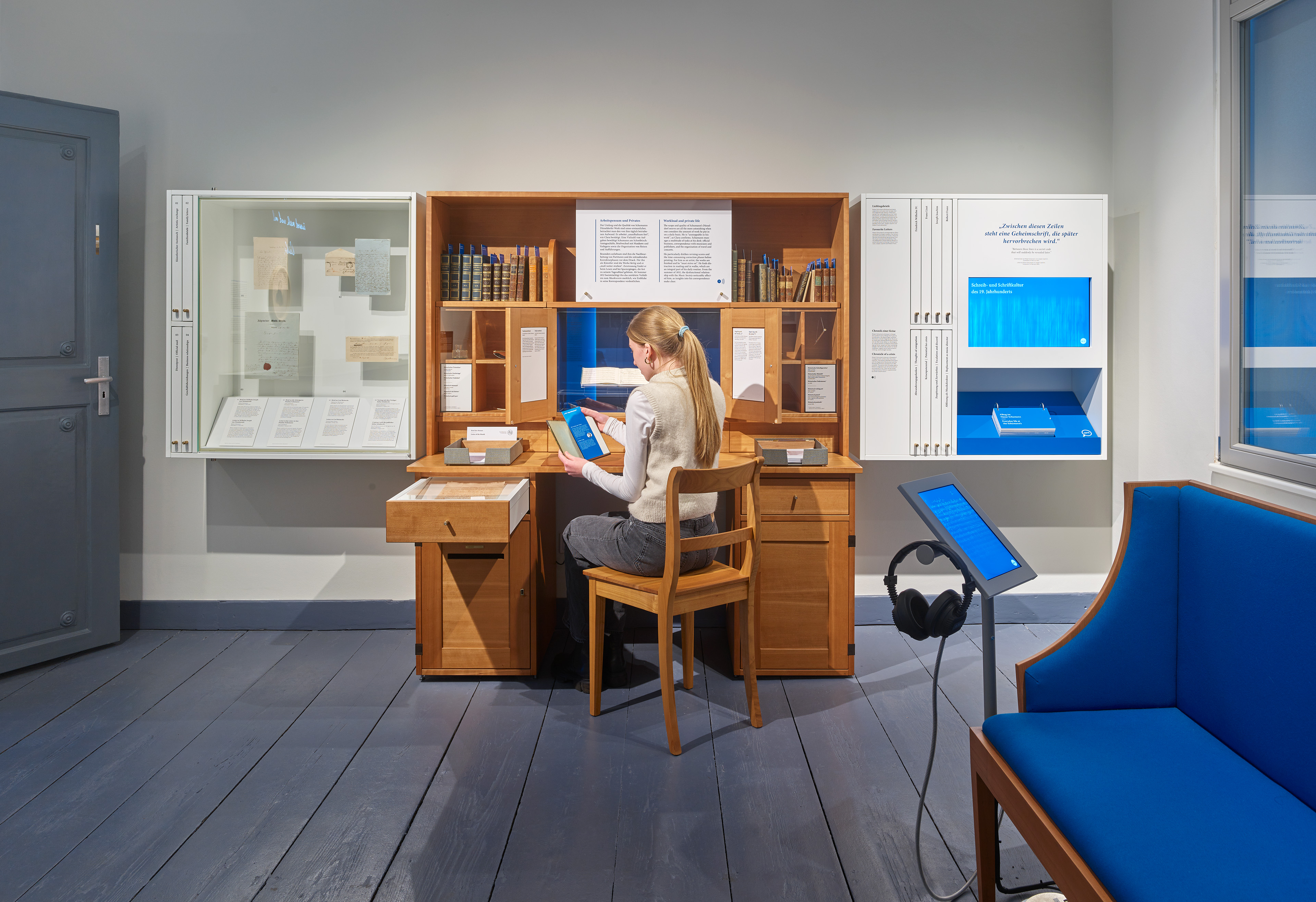 Person im Ausstellungsraum mit Ausstellungsmöbeln und verschiedenen Exponaten