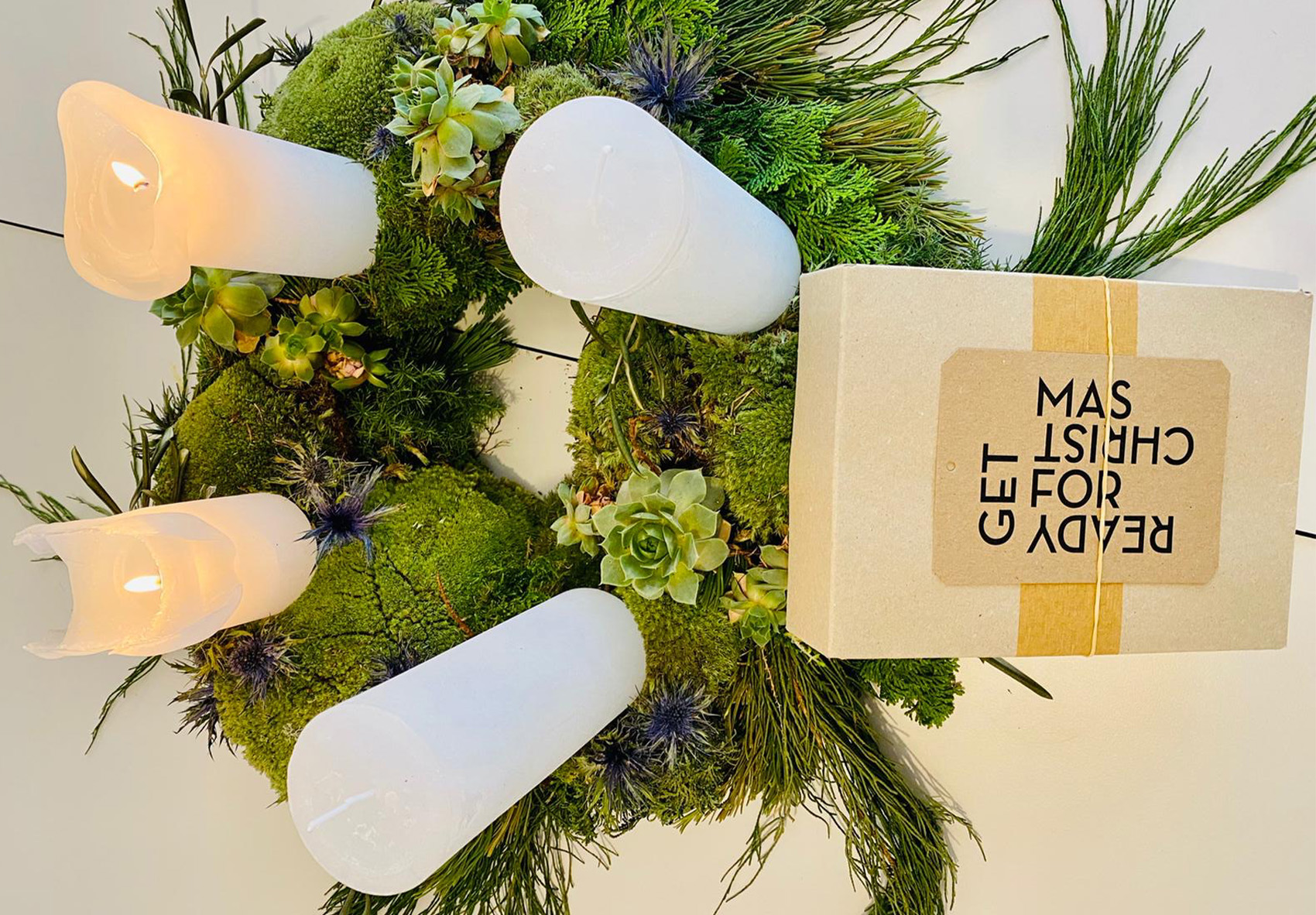 Anhänger „GET READY FOR CHRISTMAS“ arrangiert neben einem Adventskranz