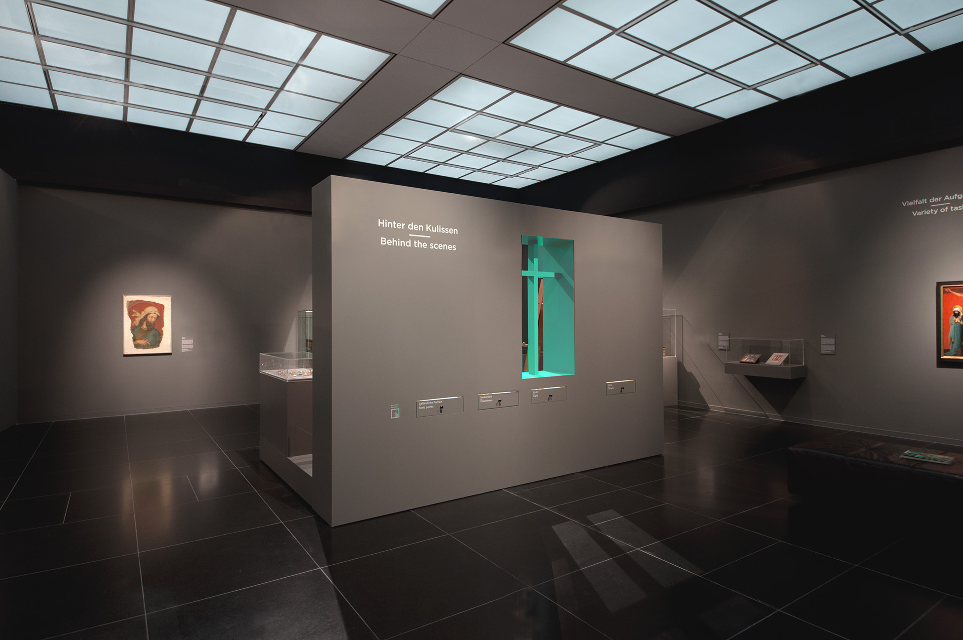 Blick in Ausstellung auf dunkelgraue Ausstellungswände mit Auszügen, Bilder und Pultvitrinen