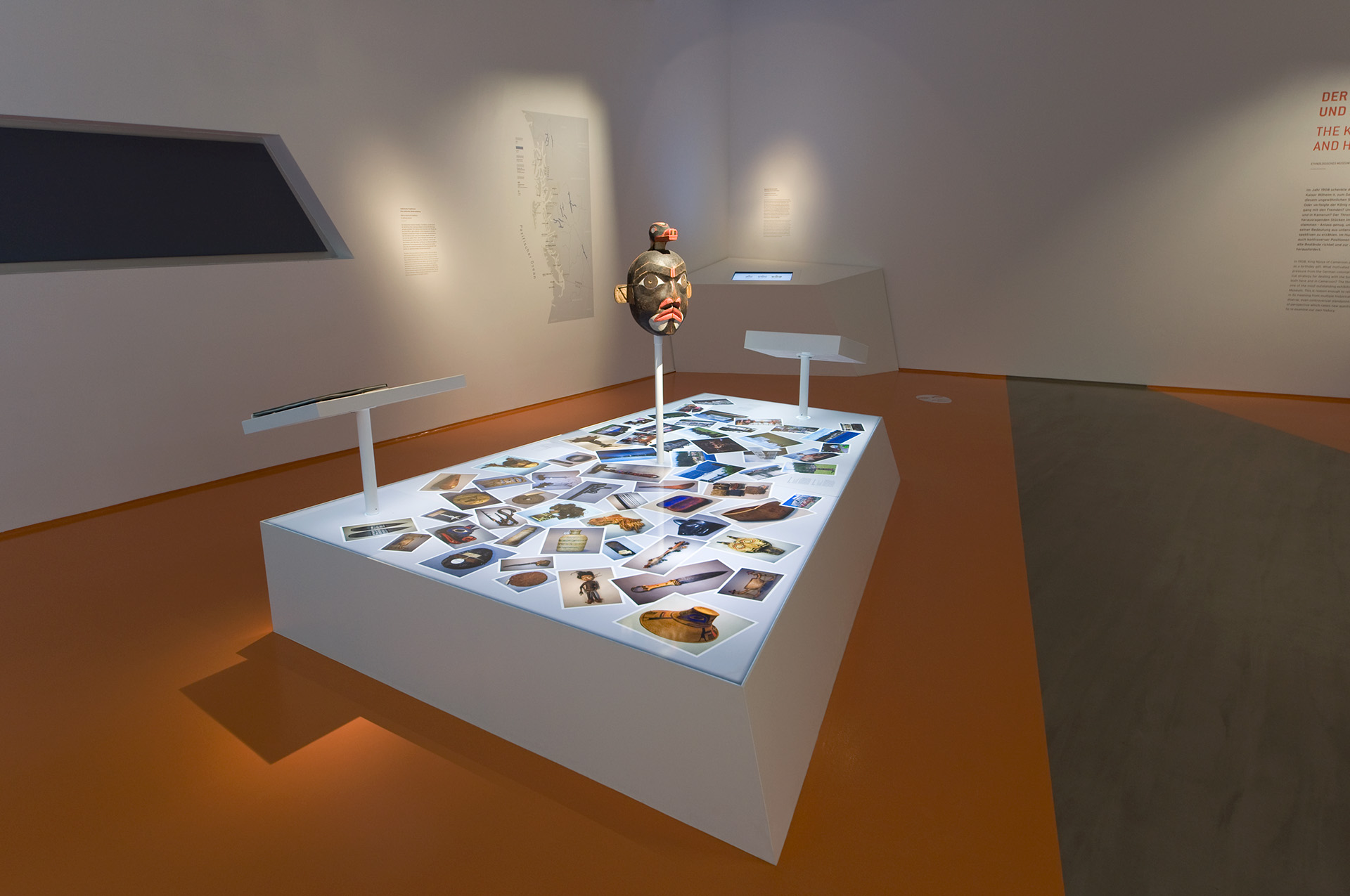 Ausstellungspodest mit Fotografien verschiedener ethnologischer Exponate