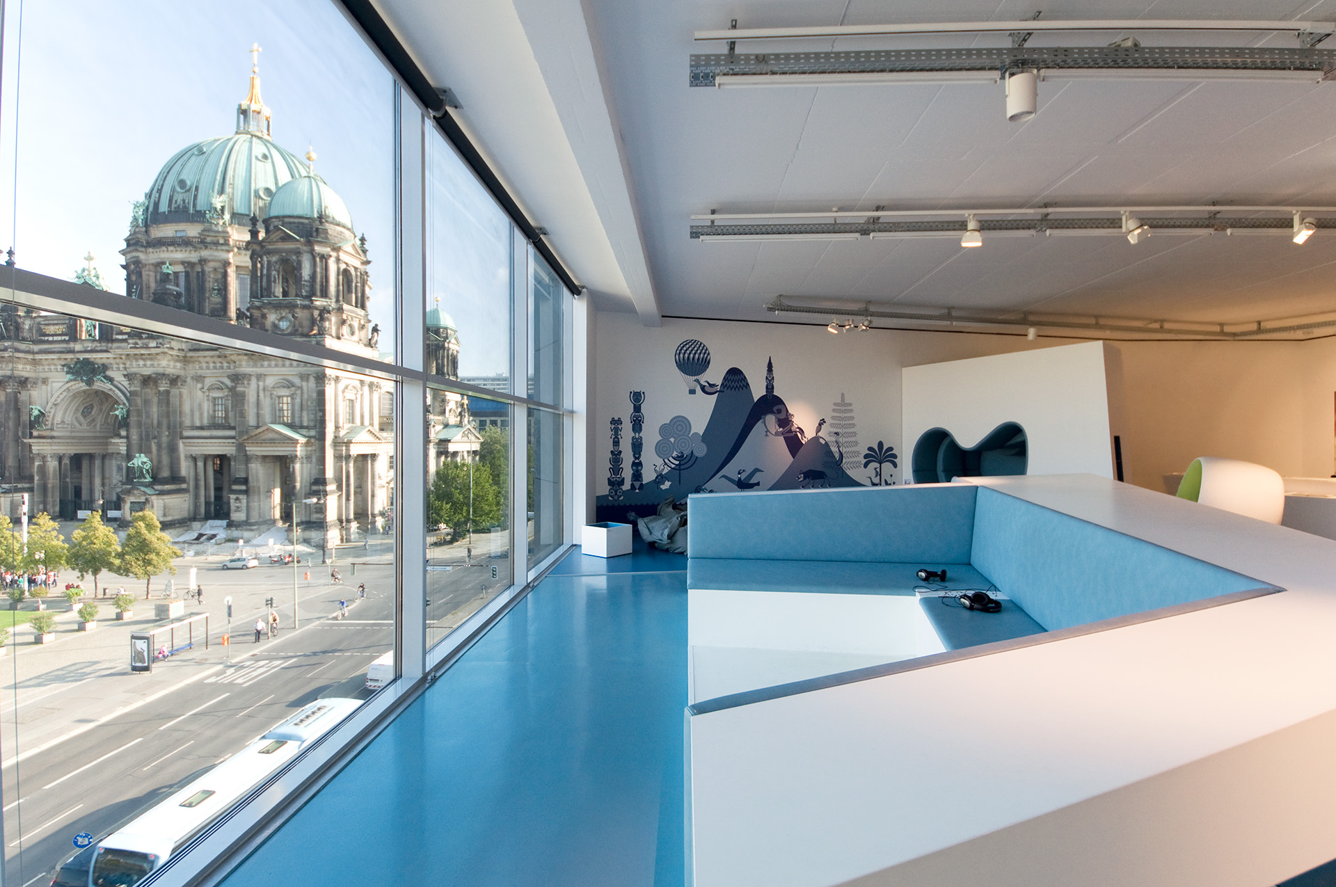 Eckige Sitzbank mit Kopfhörer ausgerichtet mit Blick in die Stadt Berlin.