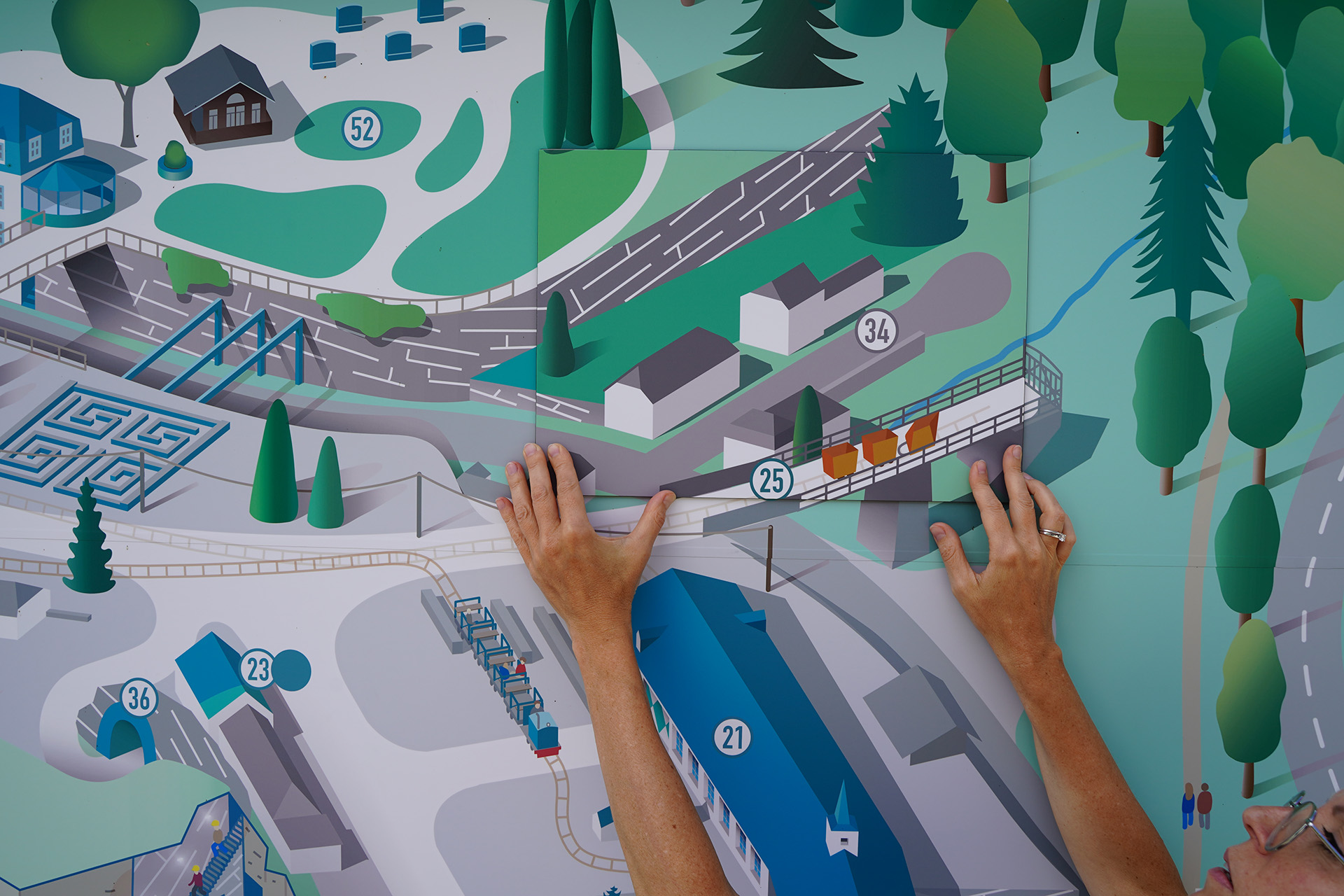 Meike hält eine Grafik vor eine große Wandgrafik, um die Farben zu vergleichen.