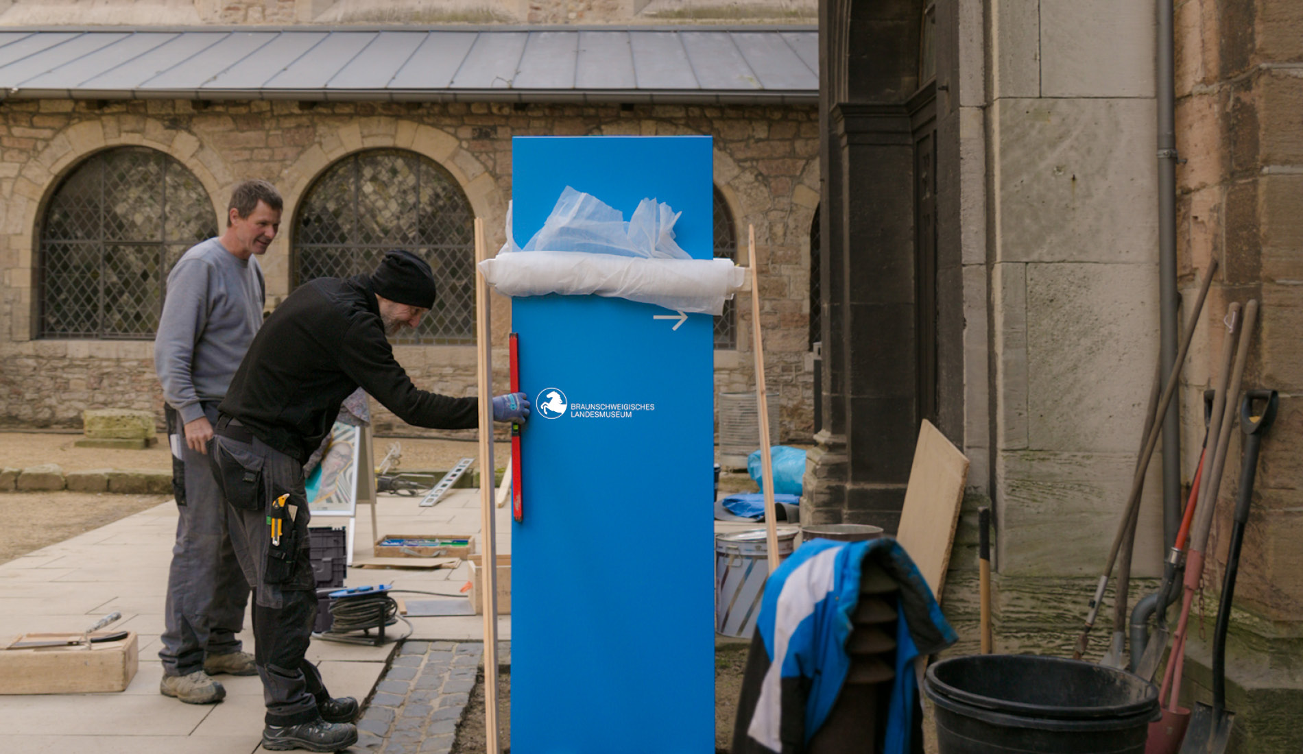 Handwerker bei der Montage eine Orientierungsstehle in Blau