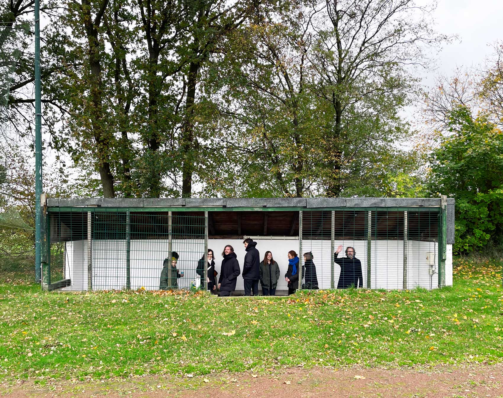 Das Team von res d steht in einem überdachten Unterstand und Ingo Plato winkt zur Kamera.